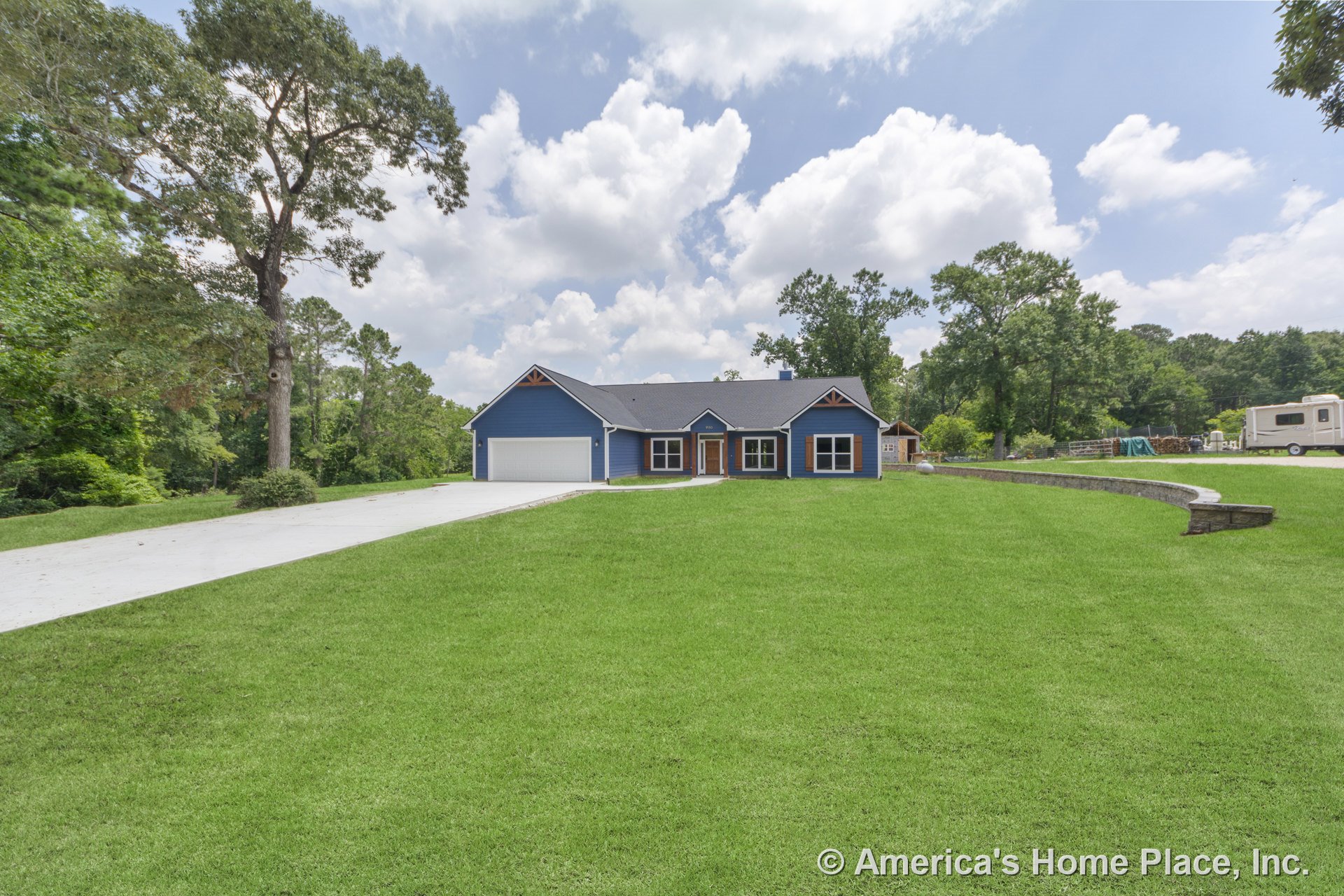 Blue siding with white trim accents, attached two-car garage, front porch supported by columns, gabled roof, concrete driveway, landscaped front yard, multiple windows, and
