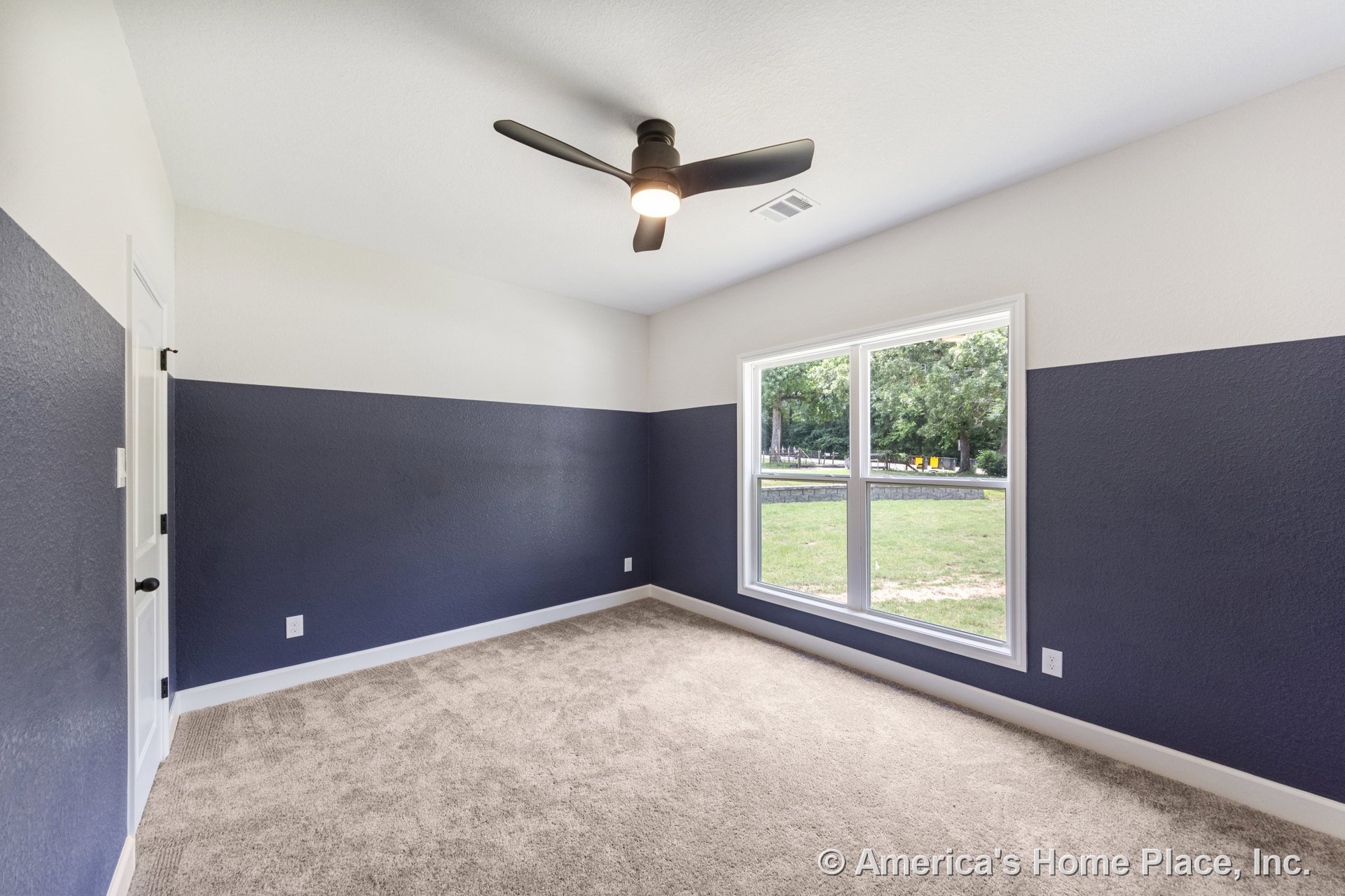 Two-tone painted bedroom walls, large double window with natural light, ceiling fan with integrated lighting, neutral carpet flooring, white trim and baseboards, paneled interior