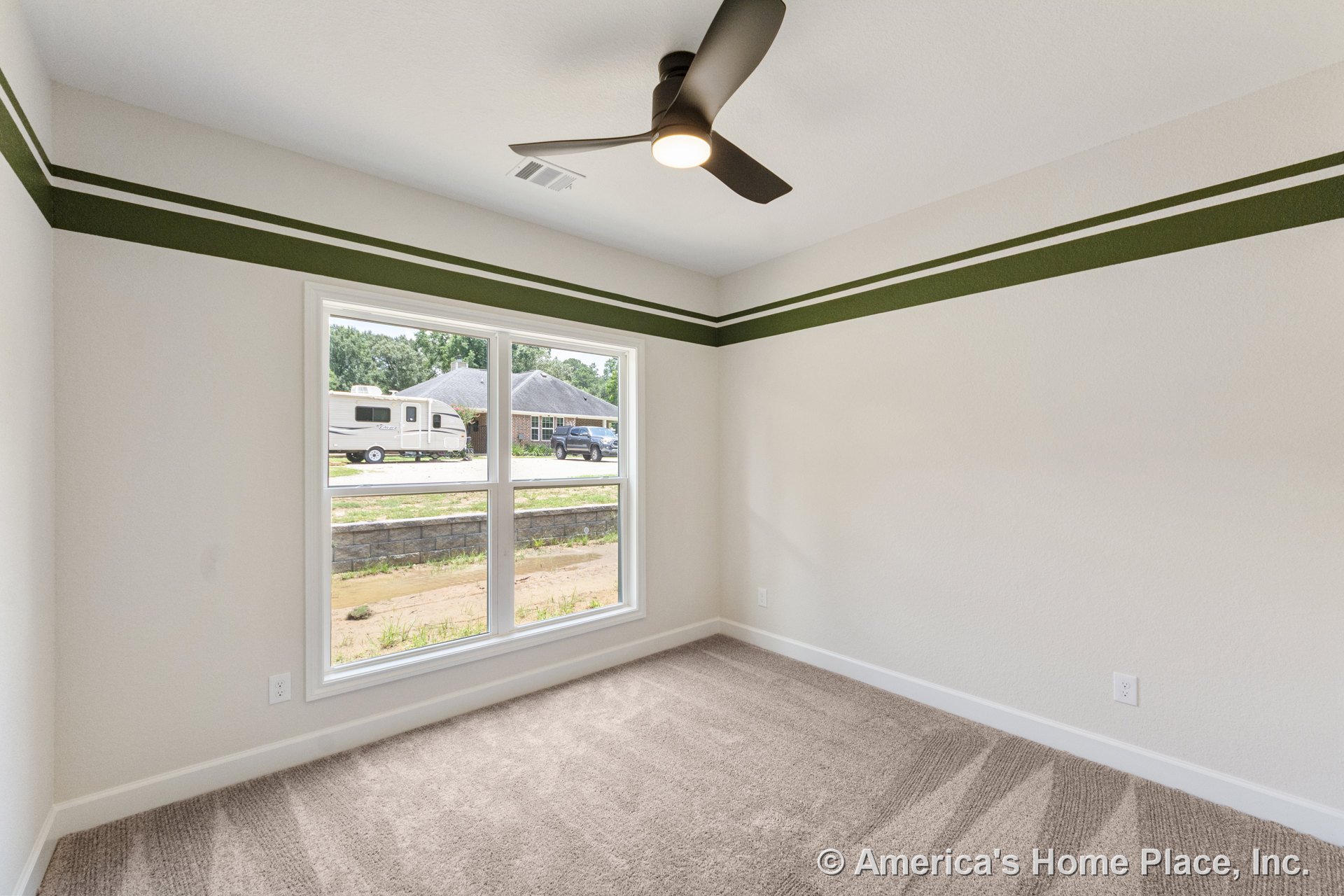 Bedroom with large double window framed in white trim, beige carpet flooring, ceiling fan with integrated light, painted green accent stripe on wall, white baseboards, and smooth
