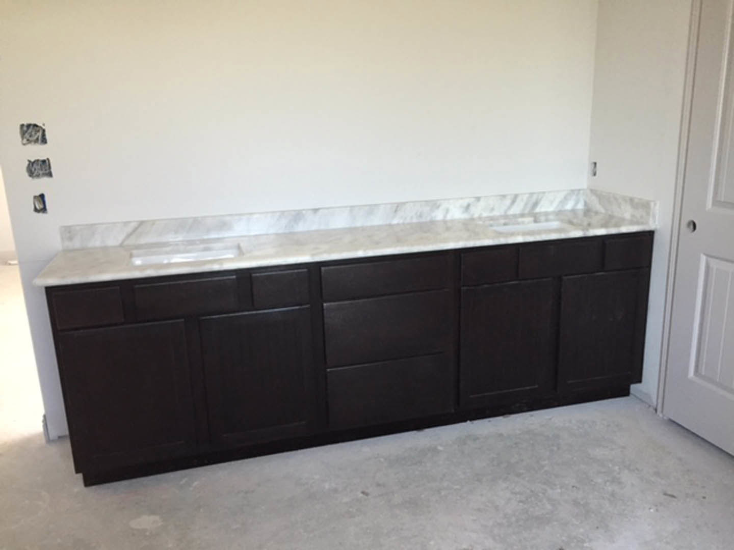 Marble countertop with undermount sink, chrome faucet, white tile backsplash, and light wood cabinetry in a modern kitchen
