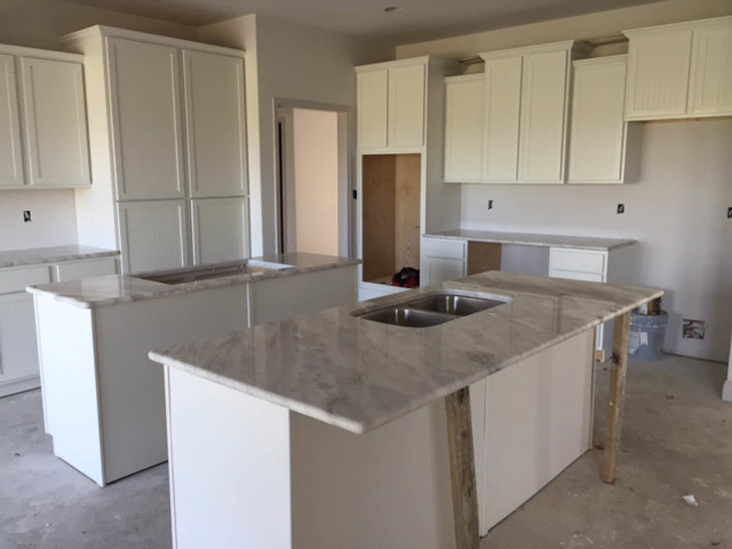 Marble countertops with undermount sink, white cabinetry, stainless steel appliances, and light-colored walls in a modern kitchen