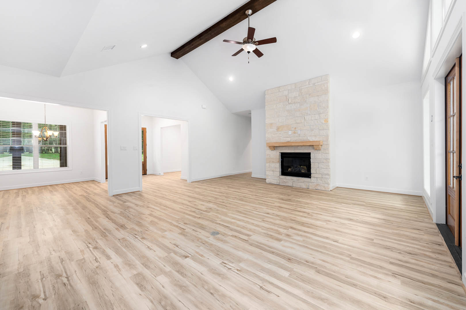 Living room with hardwood floors, plaster walls, glass-front fireplace, ceiling fan with light fixture, window with blinds, and round object centered on the floor