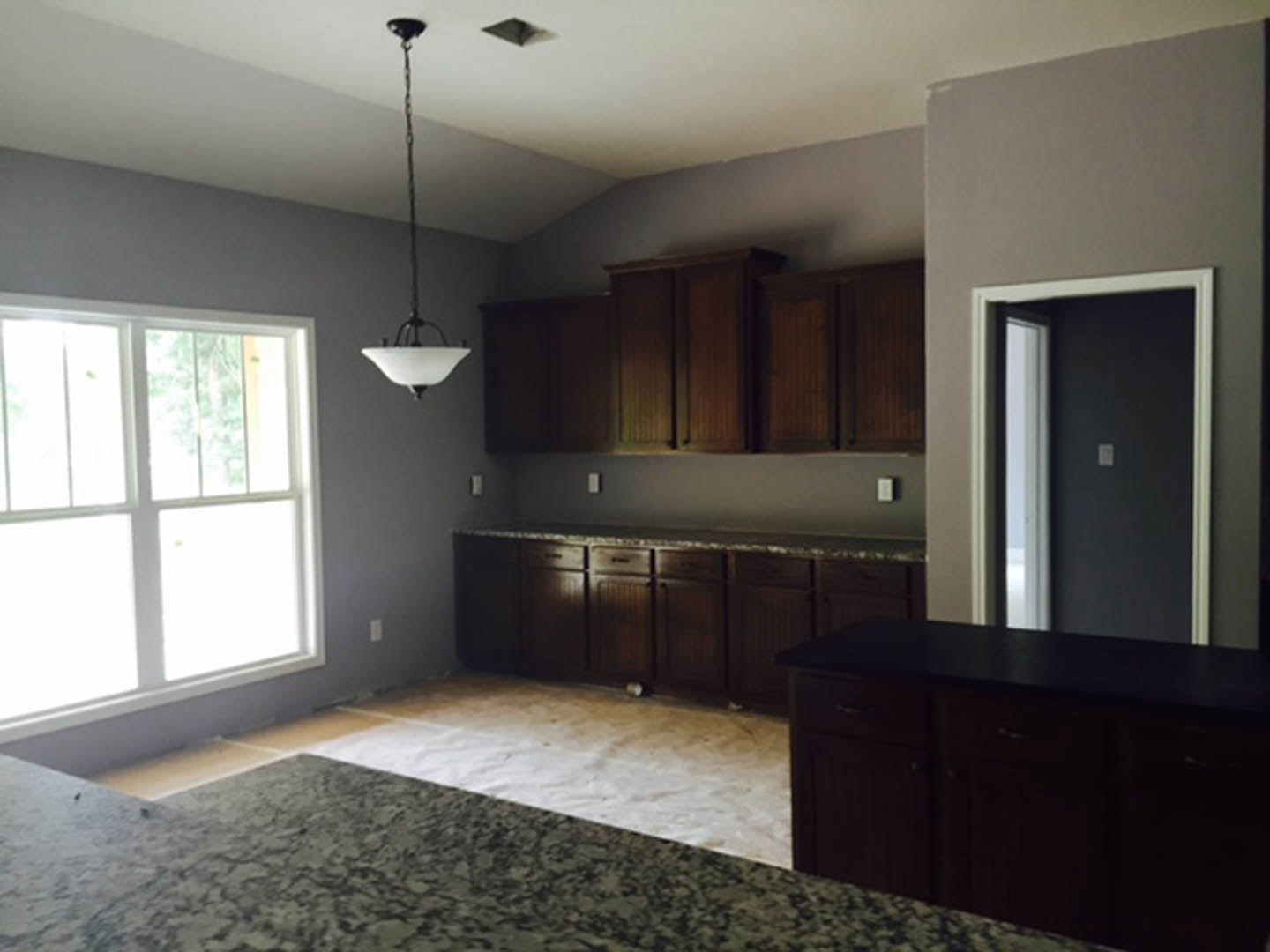 Marble tile kitchen floor, white cabinetry with dark wood drawers, stone countertop, window letting in natural light, visible cabinet and door details