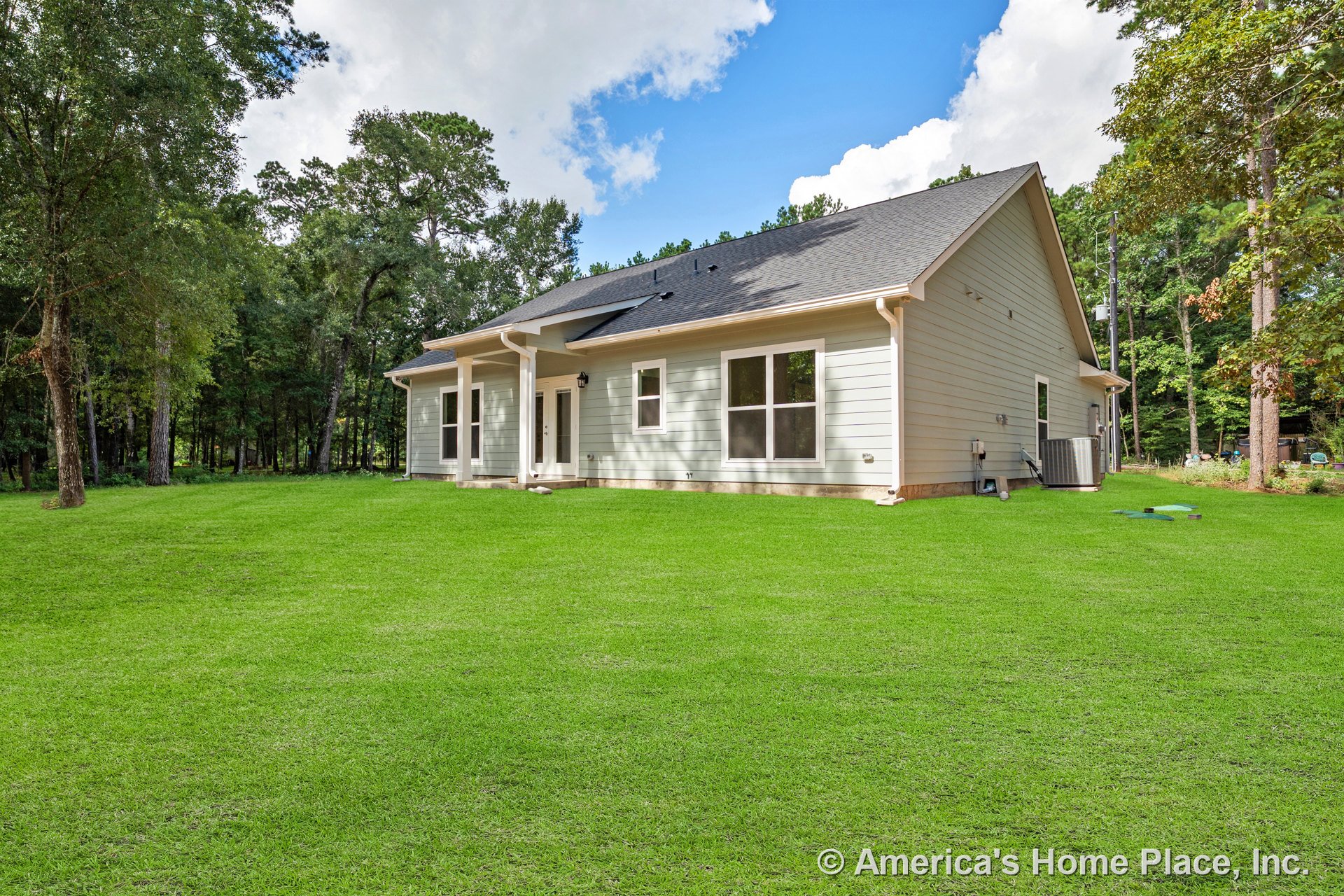 Light-colored horizontal lap siding, architectural shingle roof, white trim and gutters, multiple large windows, double exterior doors, covered rear porch with columns