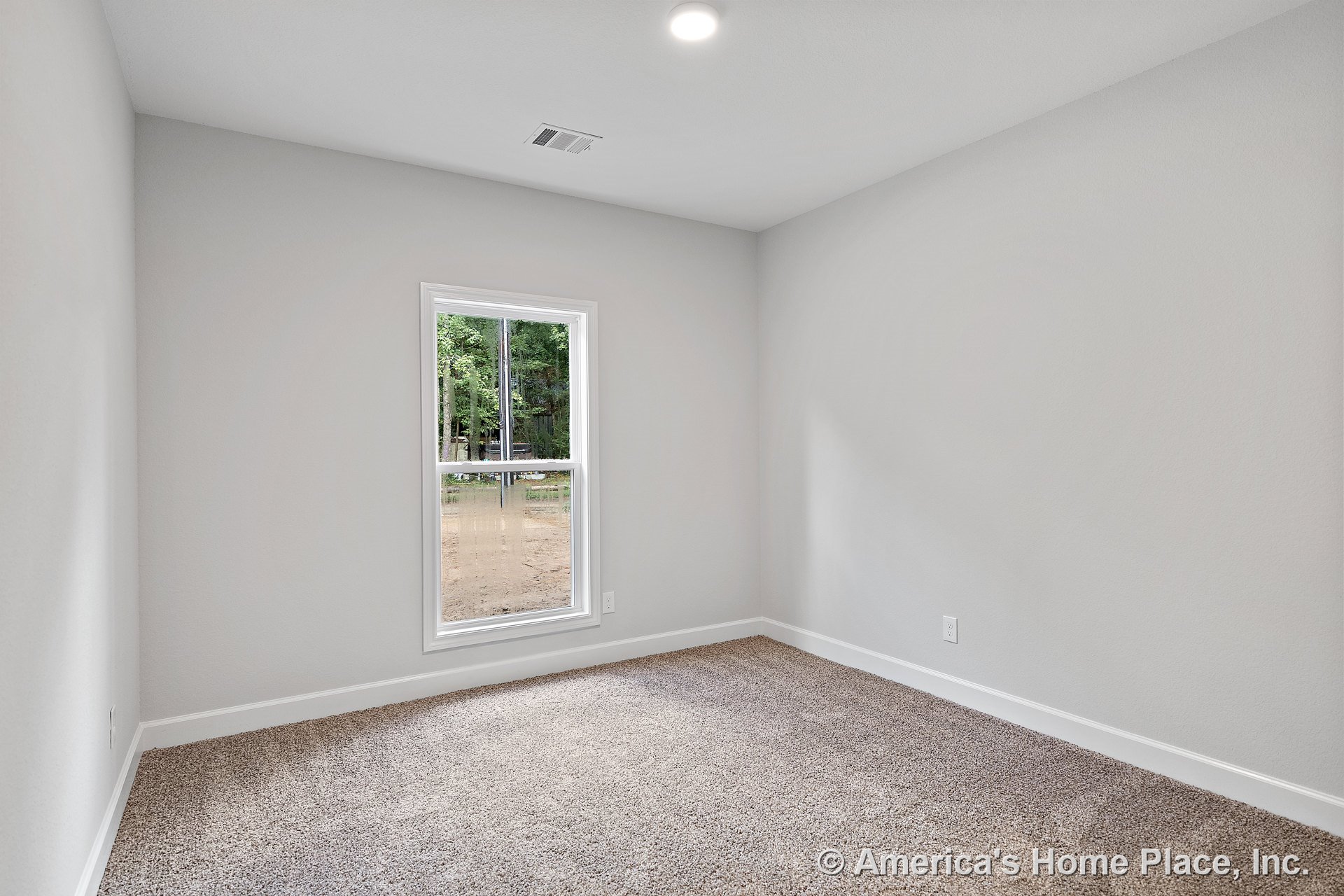 Small rectangular bedroom with light gray painted walls, carpeted floor, single window allowing natural light, white baseboard trim, and recessed ceiling light.