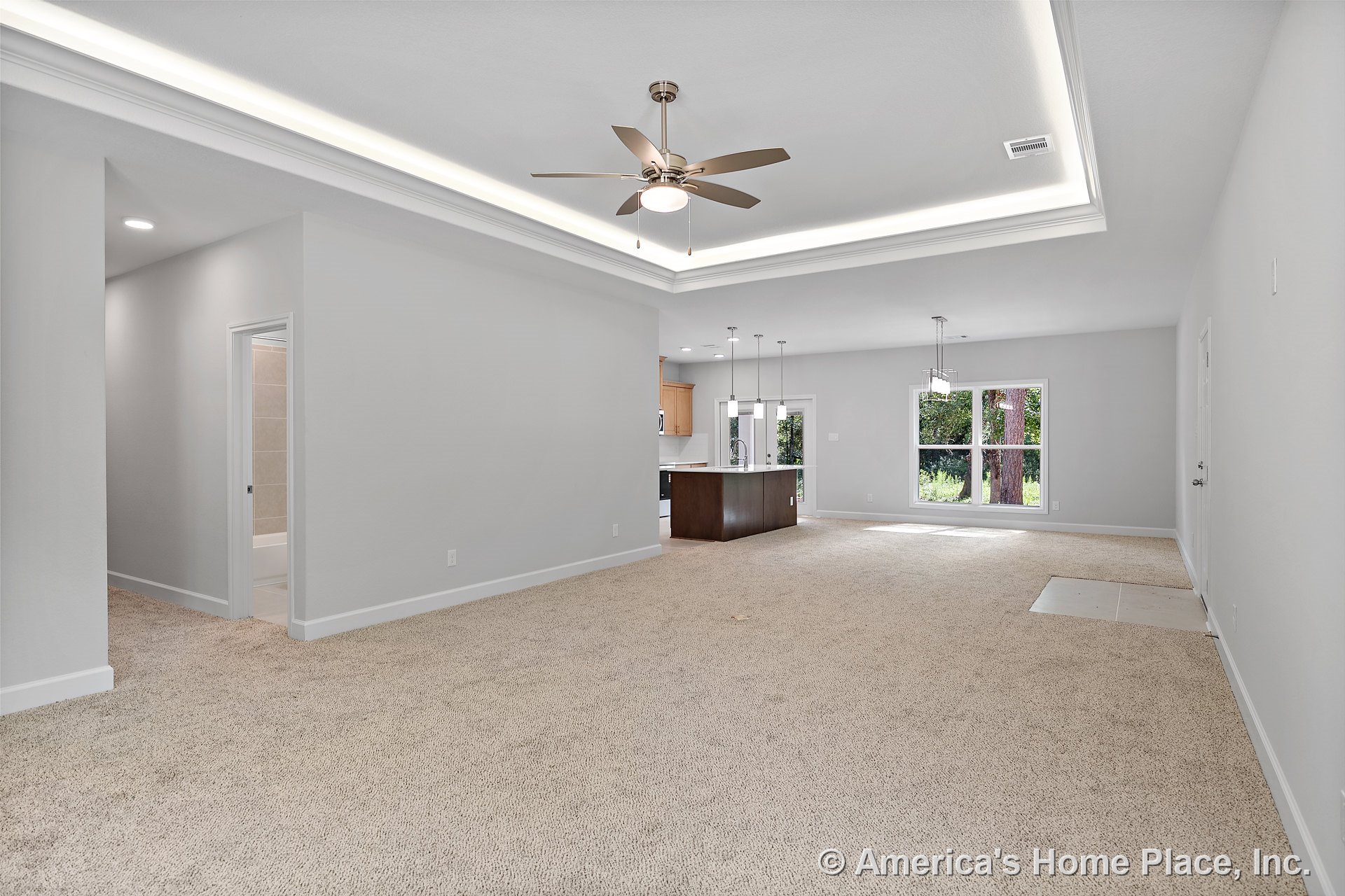 Open living area with tray ceiling, recessed LED lighting, ceiling fan, neutral carpet flooring, large dining area windows, kitchen island with pendant lights, white baseboards and