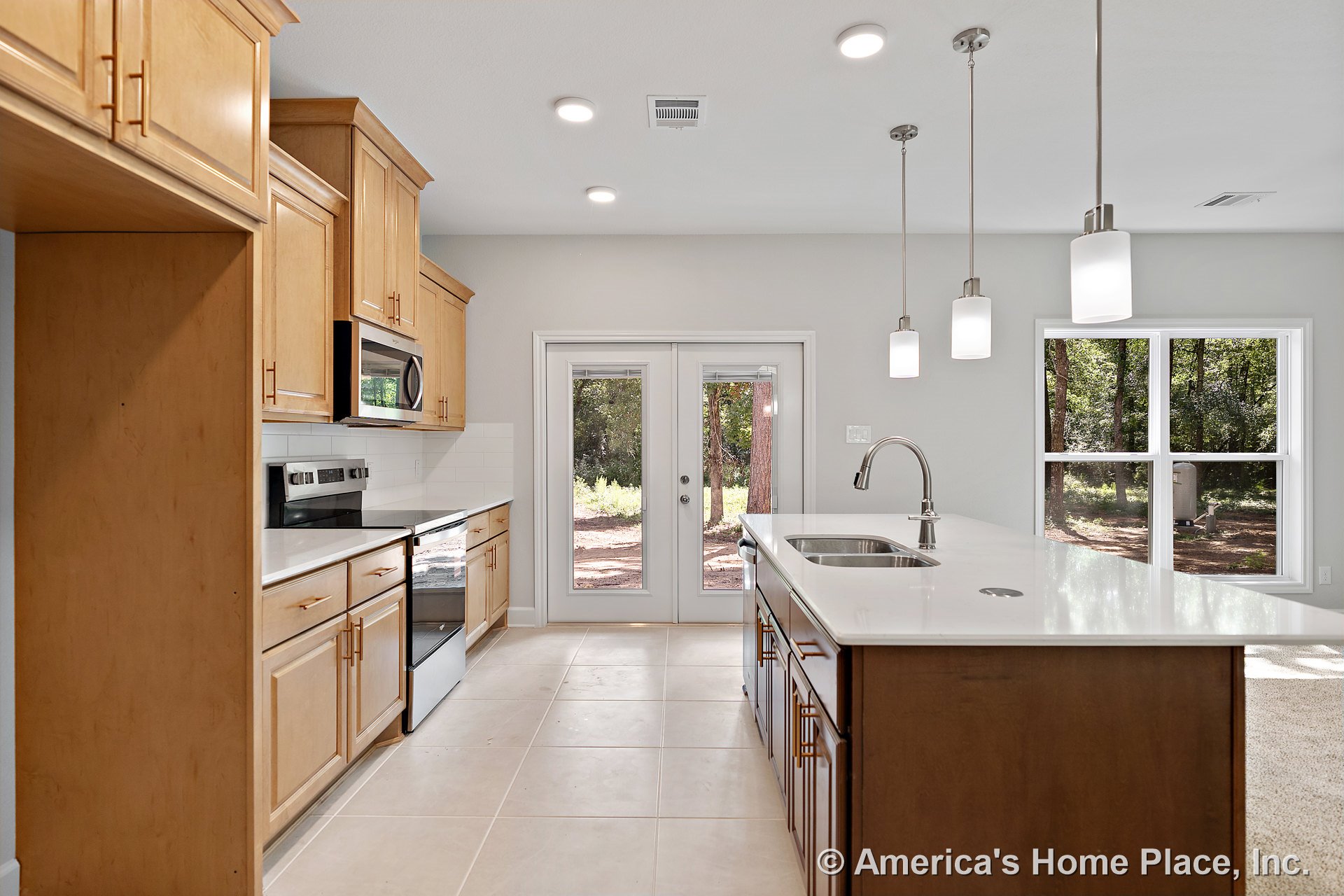 Light wood cabinets and quartz countertops surround a central island with an integrated sink, illuminated by pendant lights; tile flooring, white subway tile backsplash, stainless