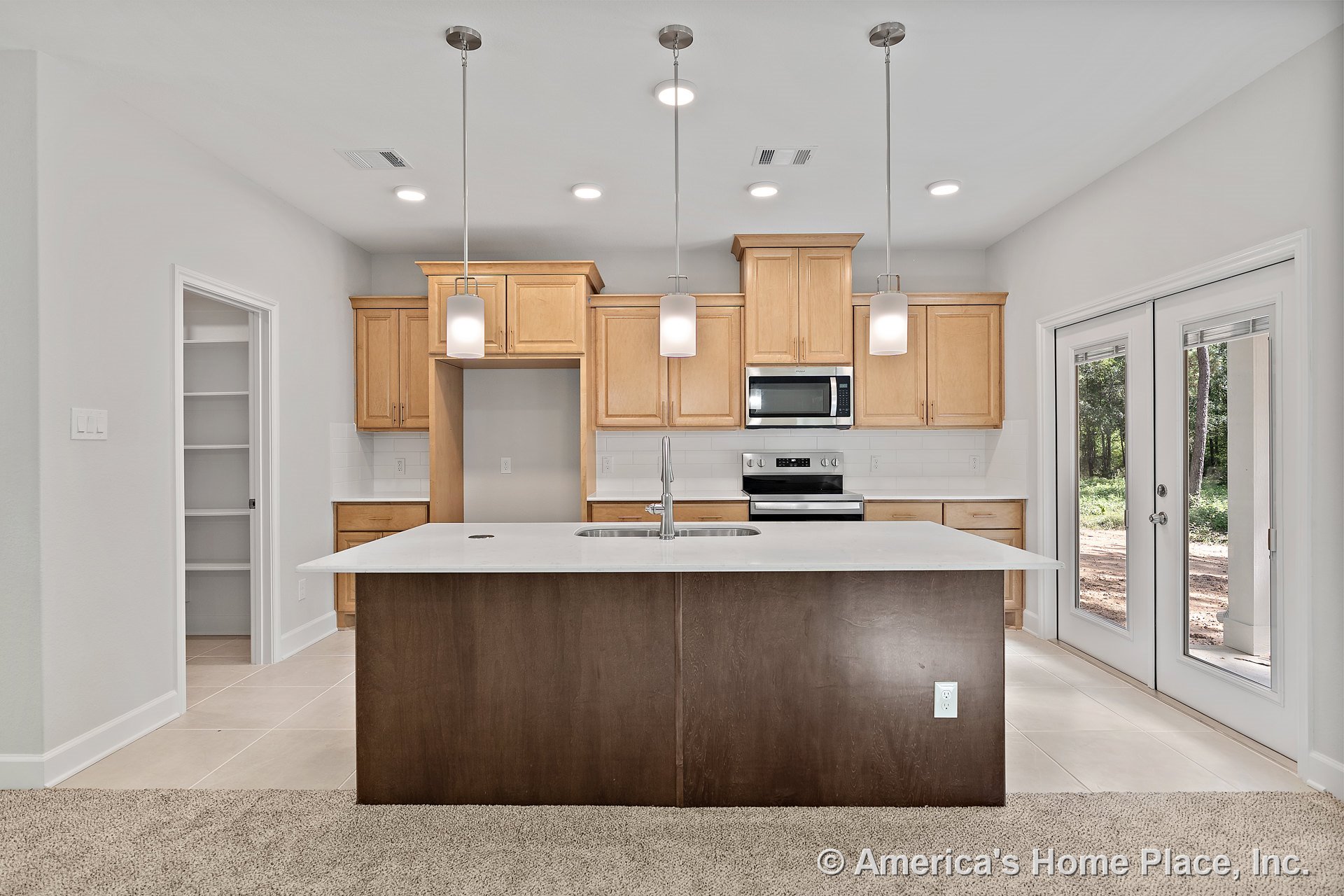 Light wood cabinetry kitchen with dark island topped by white countertop, stainless steel appliances, pendant lights above island, tile flooring, subway tile backsplash, recessed