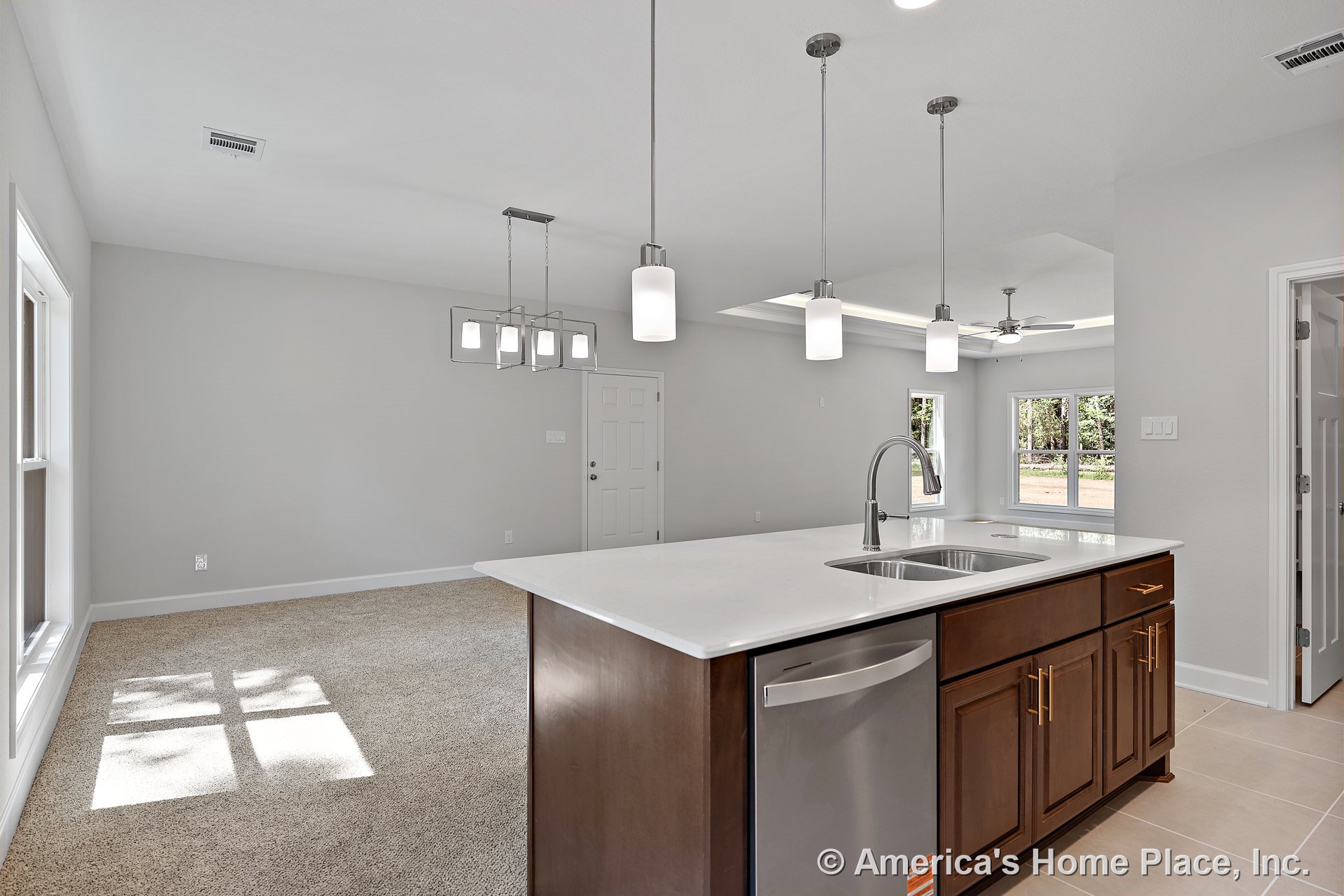 Open concept kitchen and living area with a large quartz countertop island featuring an undermount sink, dark wood cabinets with gold hardware, pendant lights above the island