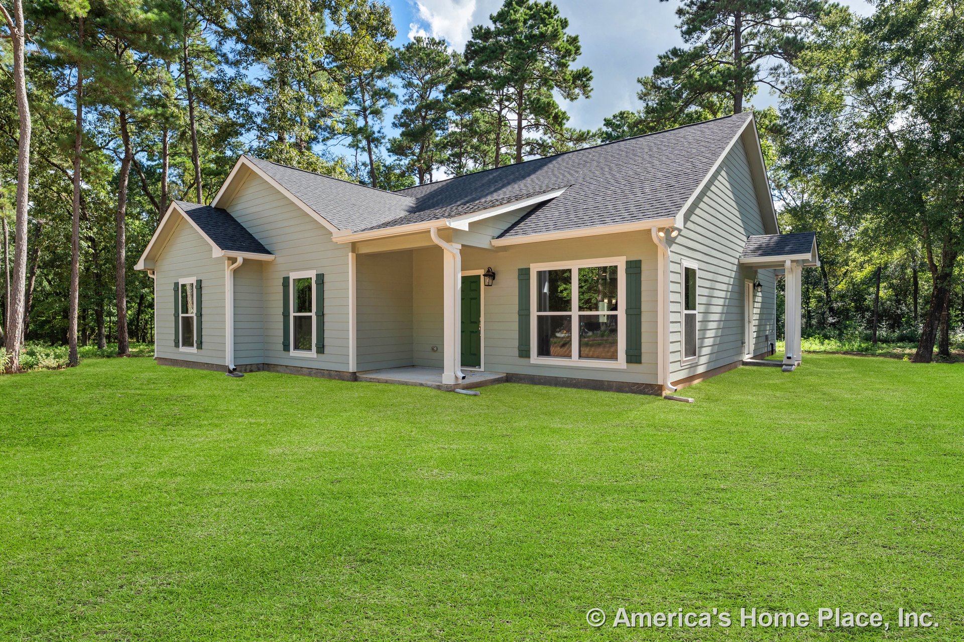 Covered front porch with gray horizontal lap siding, double-hung windows framed by green shutters, asphalt shingle roof, white trim and gutters, and wall-mounted exterior lantern.