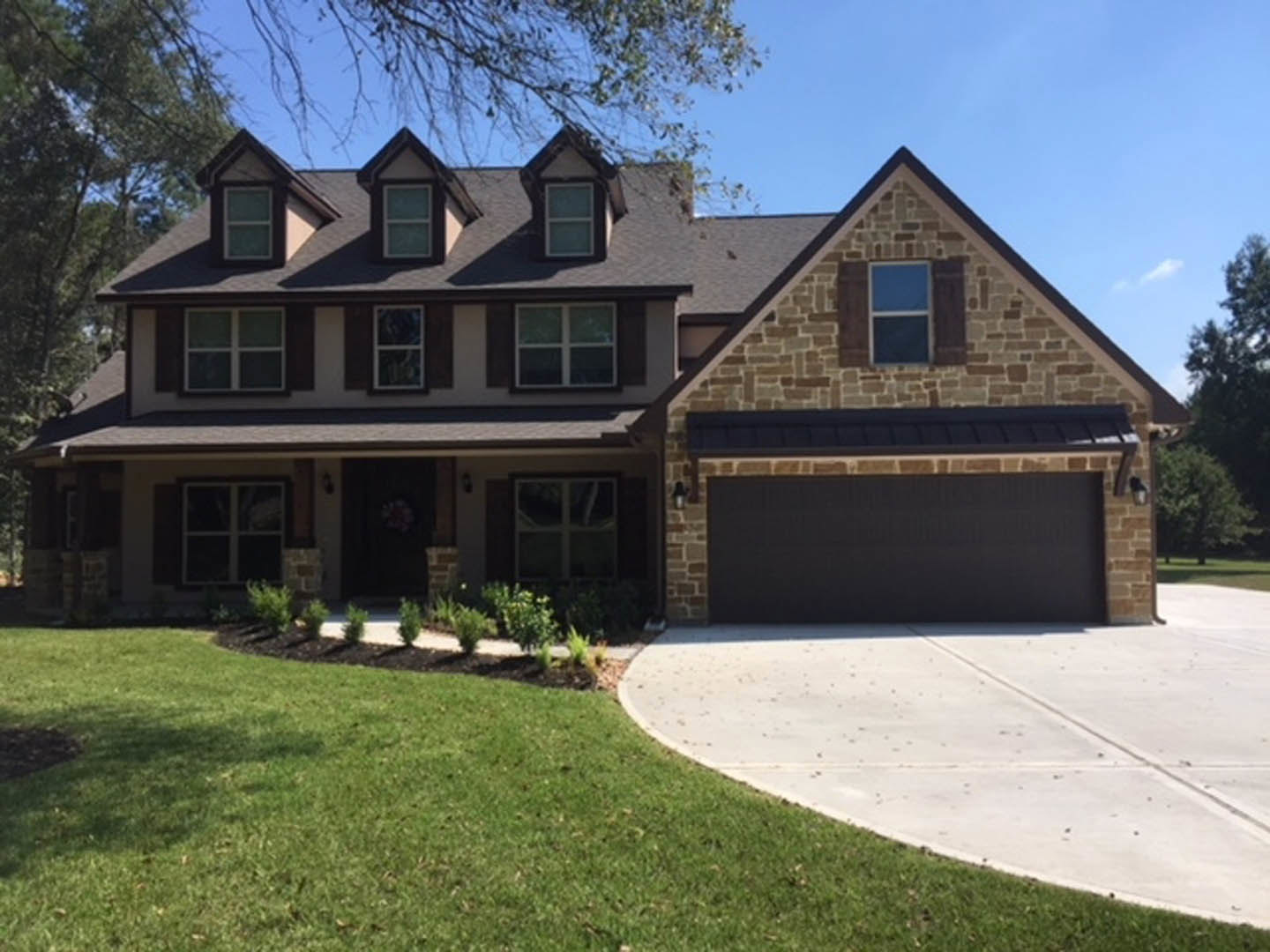 Two-story house with white siding, attached garage, concrete driveway, manicured lawn, front porch, and multiple windows