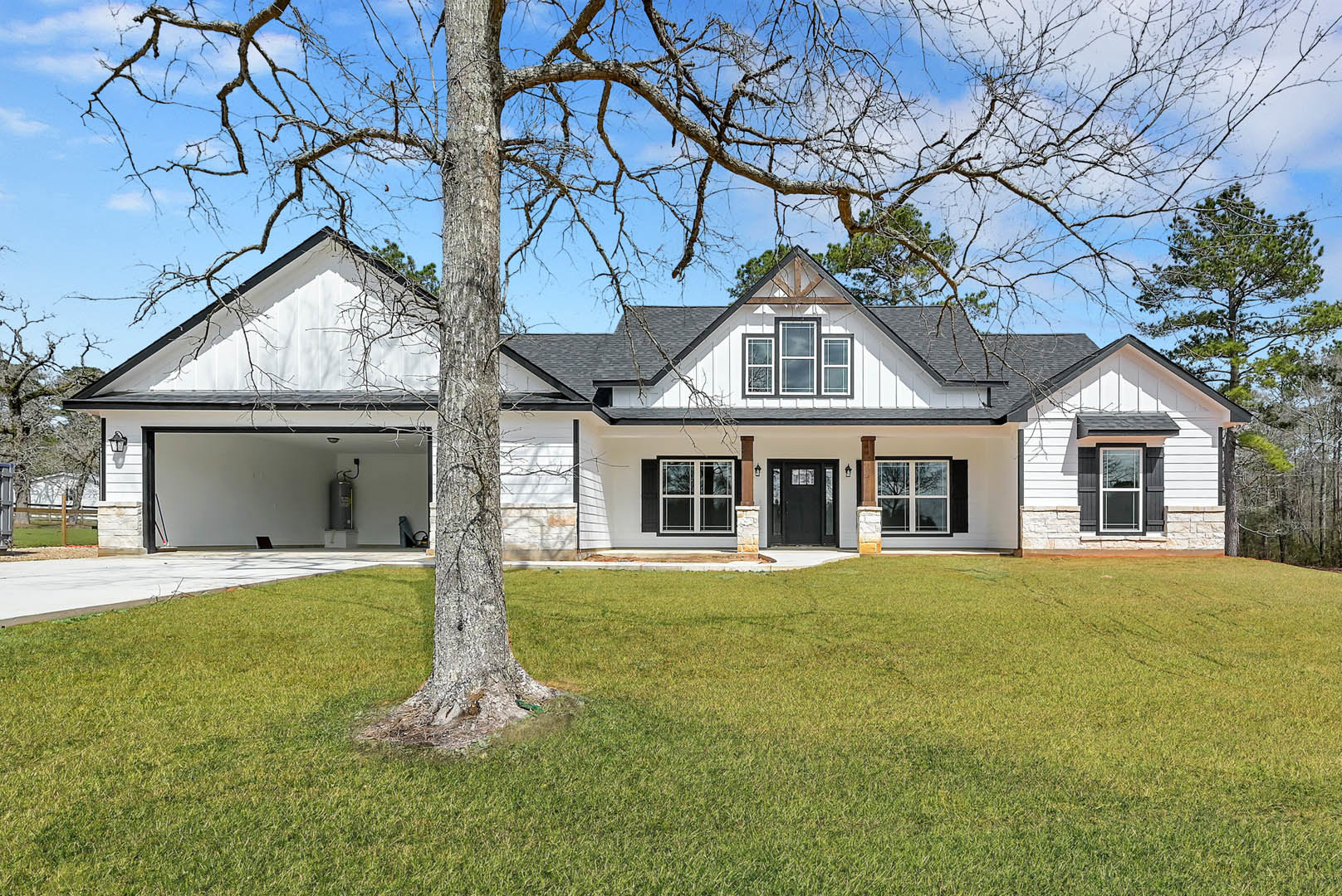 White two-story house with black front door, white-framed windows, green lawn, and mature tree in the yard