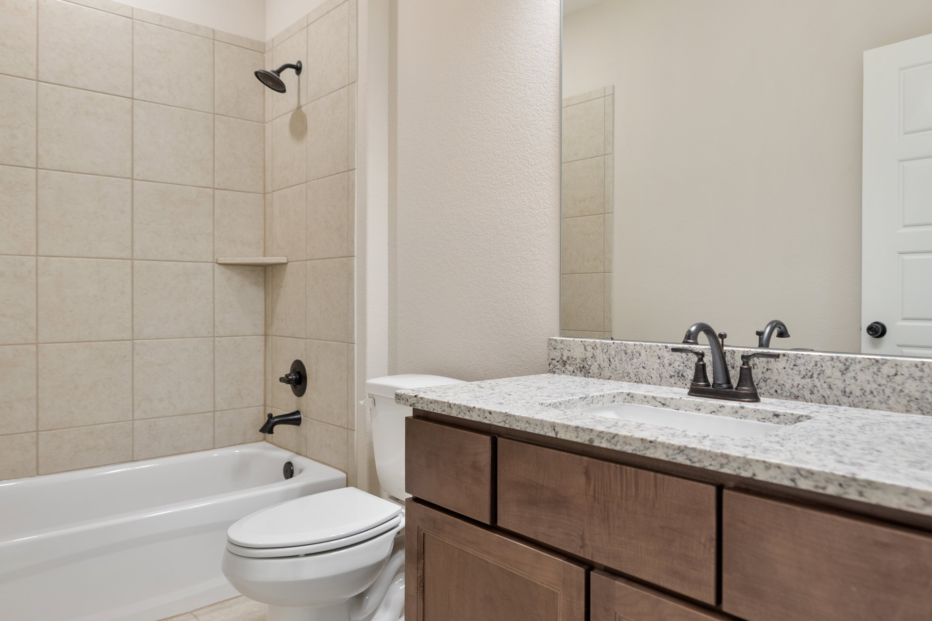 White porcelain toilet and rectangular sink with chrome faucet, light gray tile flooring, white paneled door, neutral painted walls