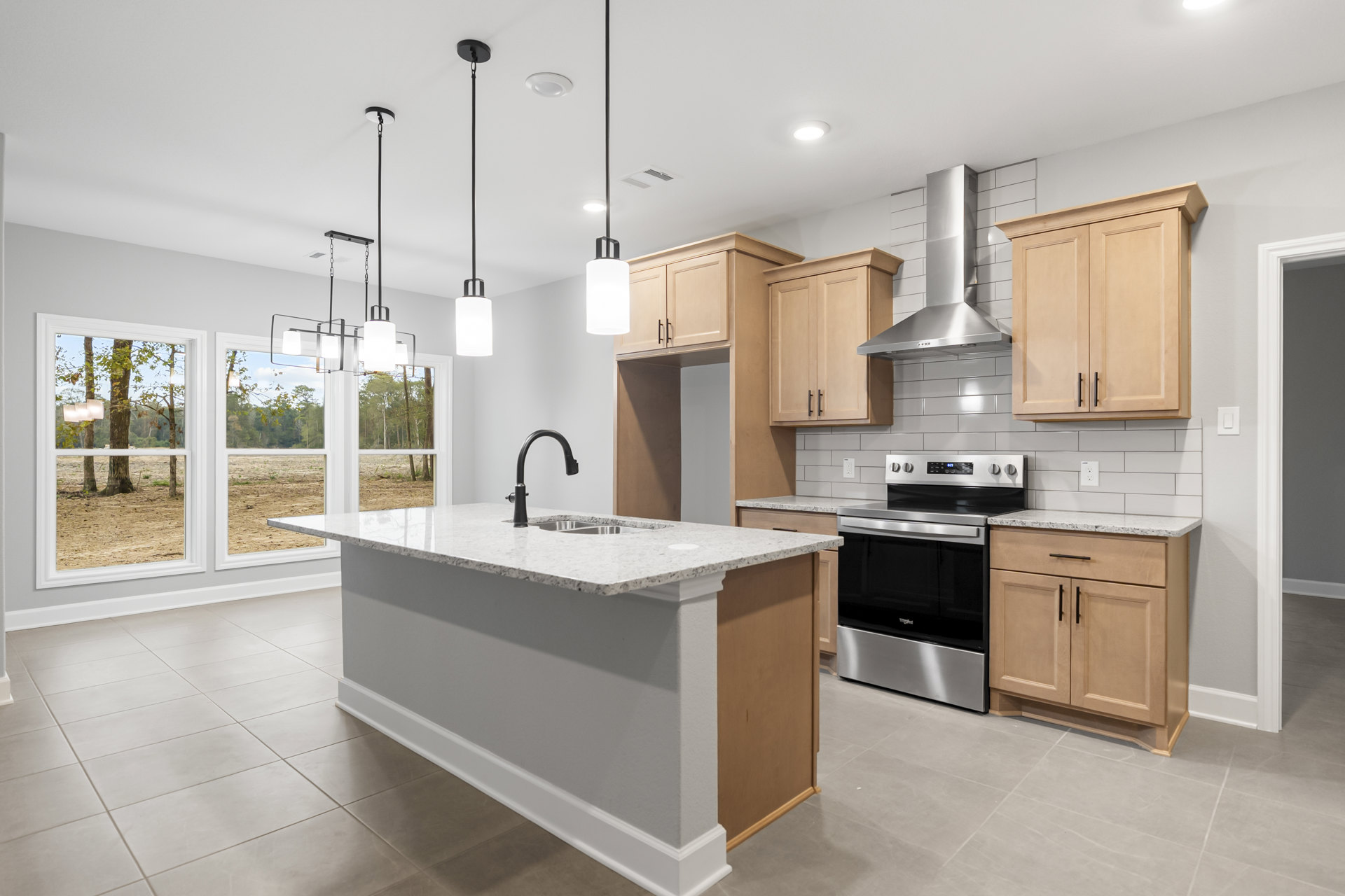Open kitchen with wood cabinets and black handles, central island featuring a sink and black faucet, stainless steel stove, light countertops, tile backsplash, and pendant lighting