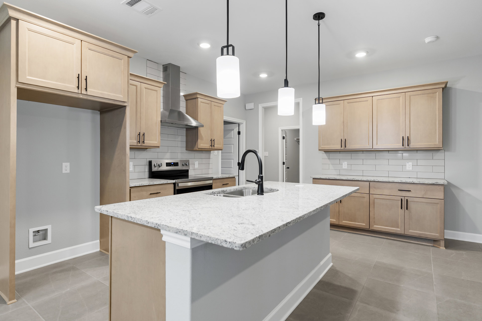 Modern kitchen with white cabinetry, granite countertops, tile backsplash, central island featuring a black faucet and undermount sink, and sleek plumbing fixtures