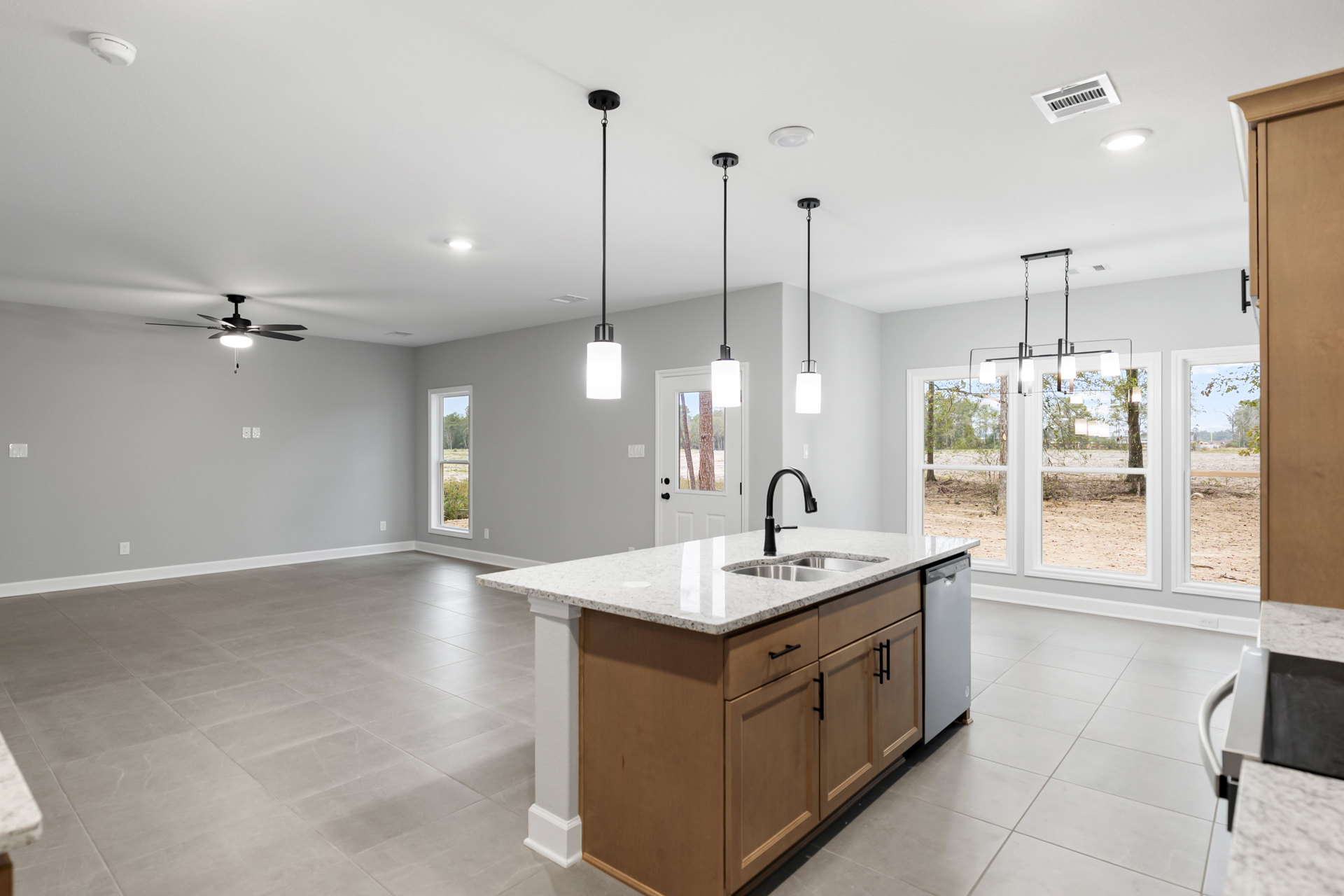 Spacious kitchen featuring a large central island with built-in sink, white cabinetry, tile flooring, ceiling fan, and recessed lighting.