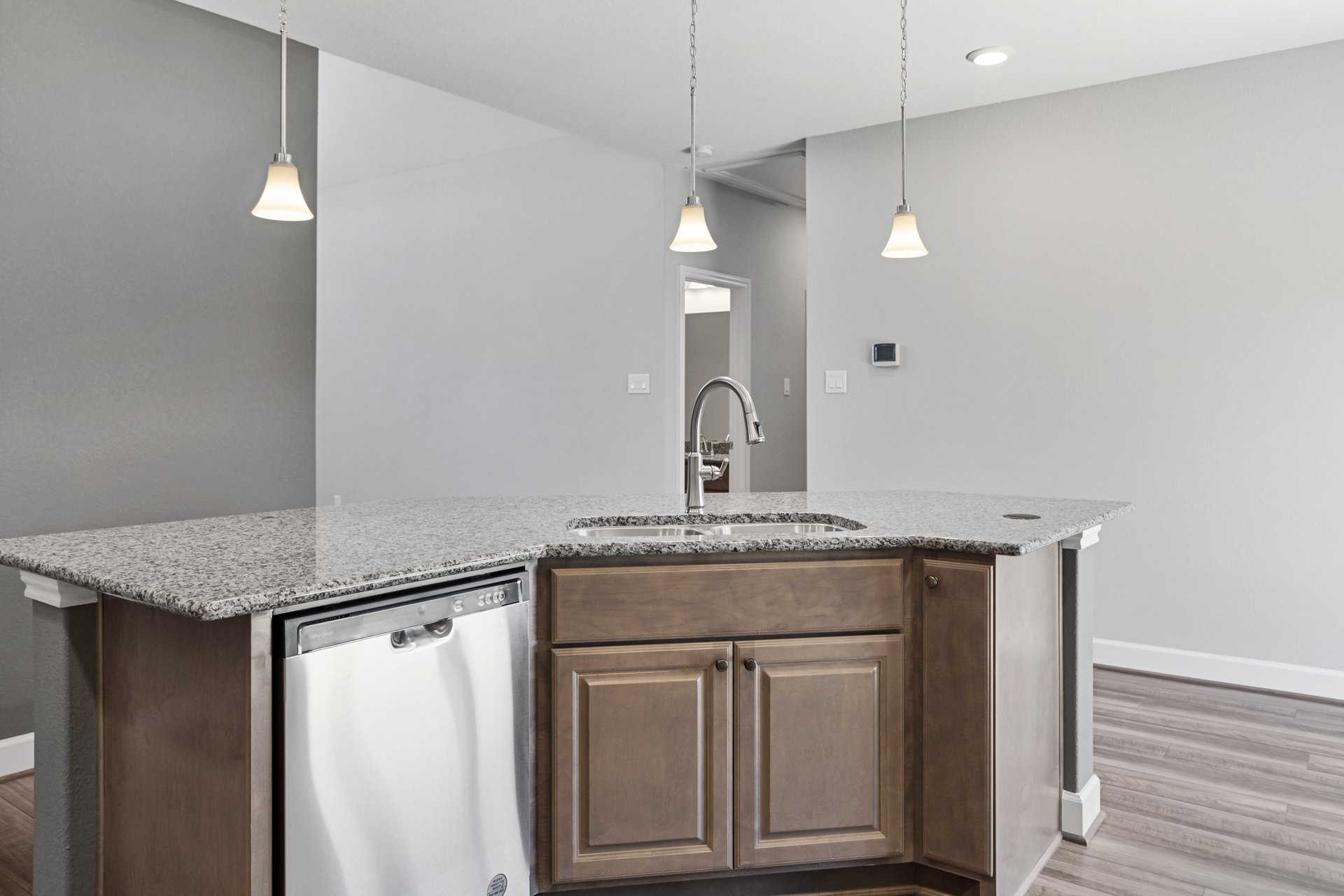 Marble countertop with undermount sink, stainless steel dishwasher, white cabinetry, chrome faucet, and black cabinet handles in a modern kitchen.