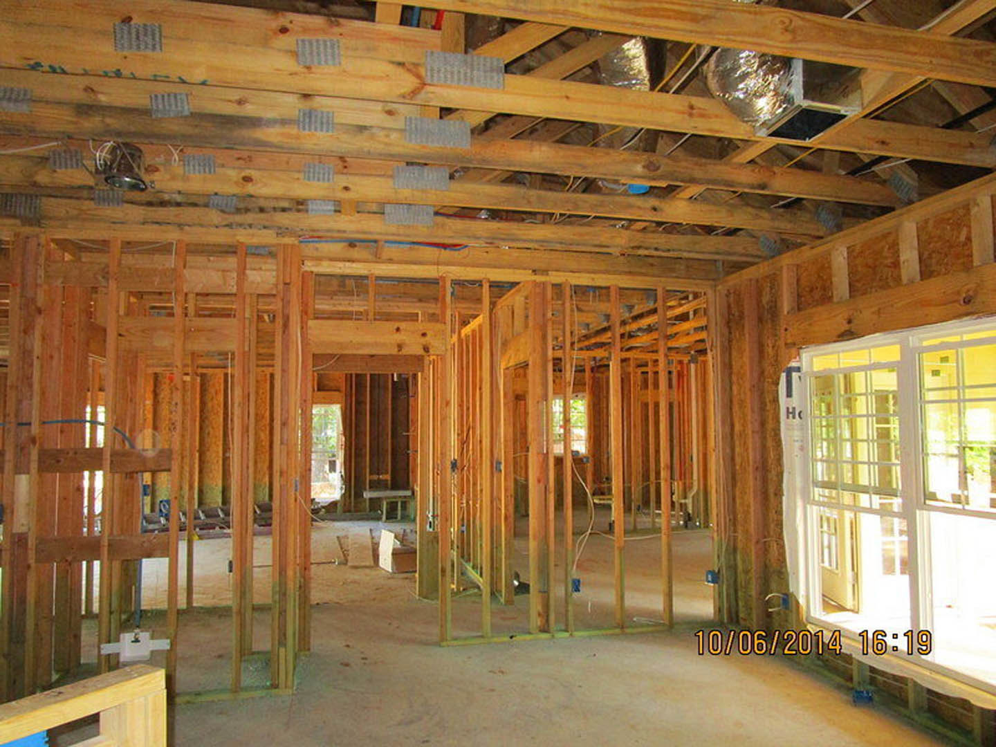 Exposed wood beams and framing inside a partially constructed home with unfinished walls, ceiling, and floor