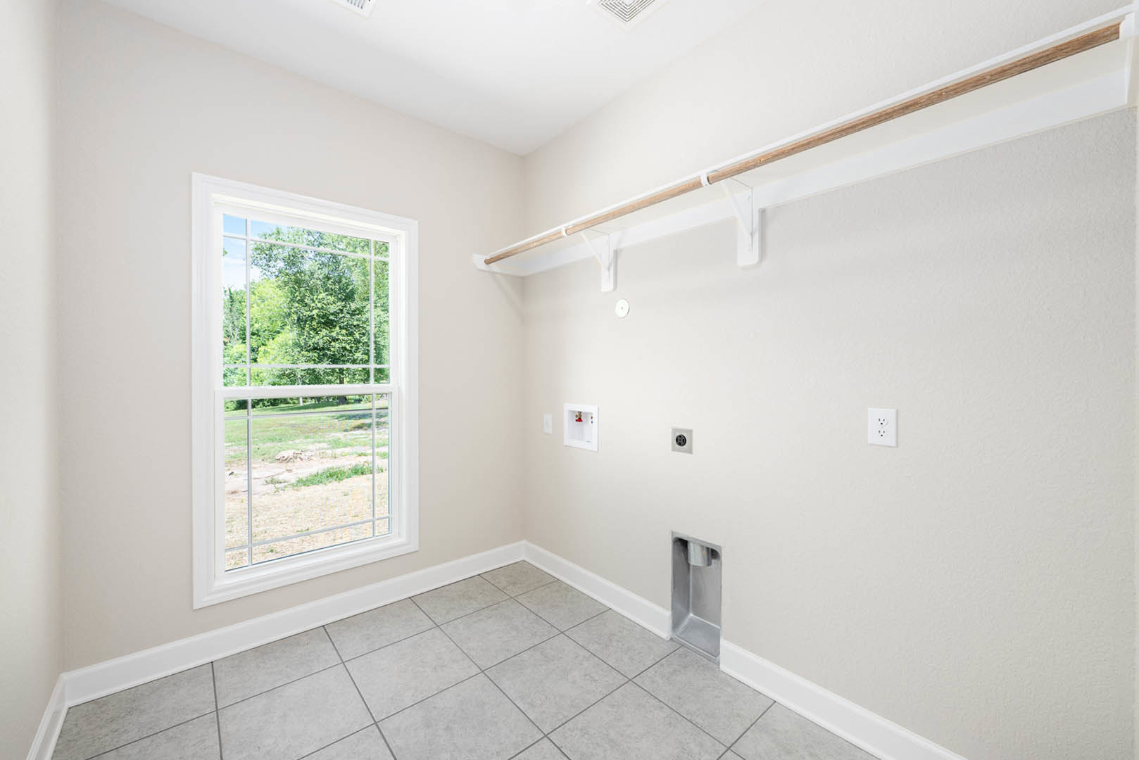Bar area with wood countertop, chrome faucet, white walls, large window overlooking trees, white curtain rod, and white electrical outlet with black dots