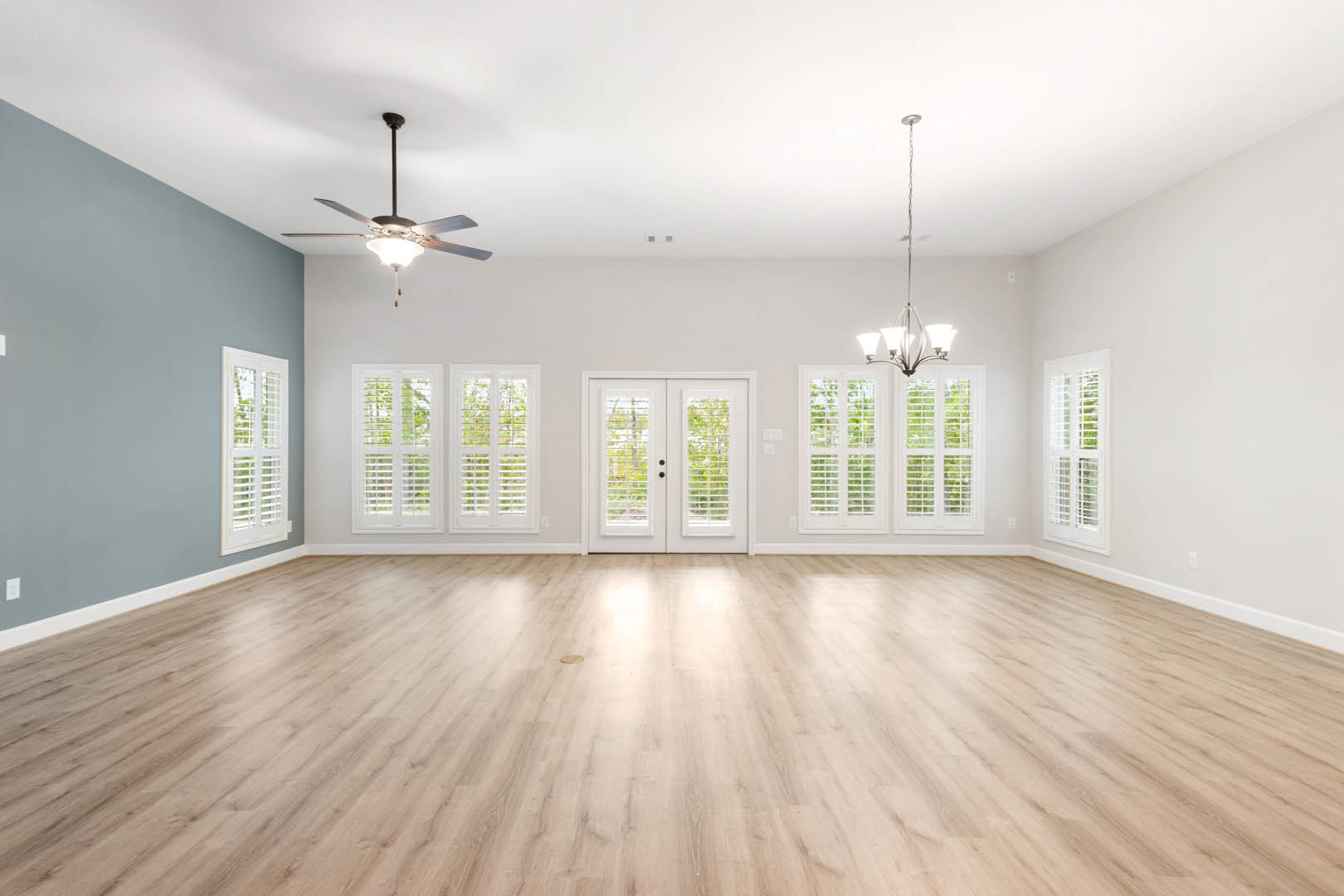 Hardwood flooring, white double doors with blinds, ceiling fan with light fixture, plaster walls, close-up window, wood finishes throughout