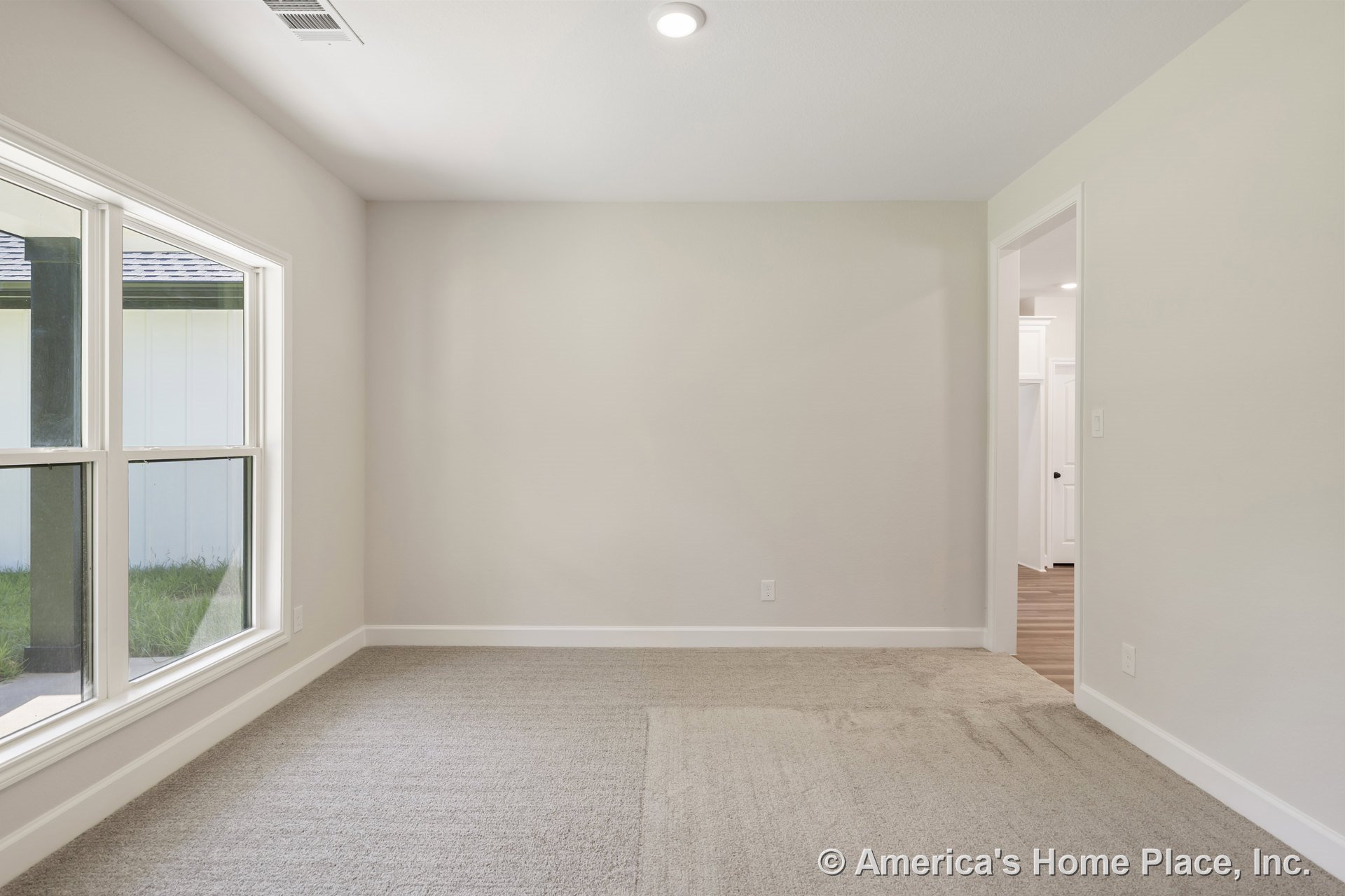 Carpeted room with neutral wall paint, white baseboards, large double-pane windows, recessed ceiling lighting, and doorway leading to adjacent space.
