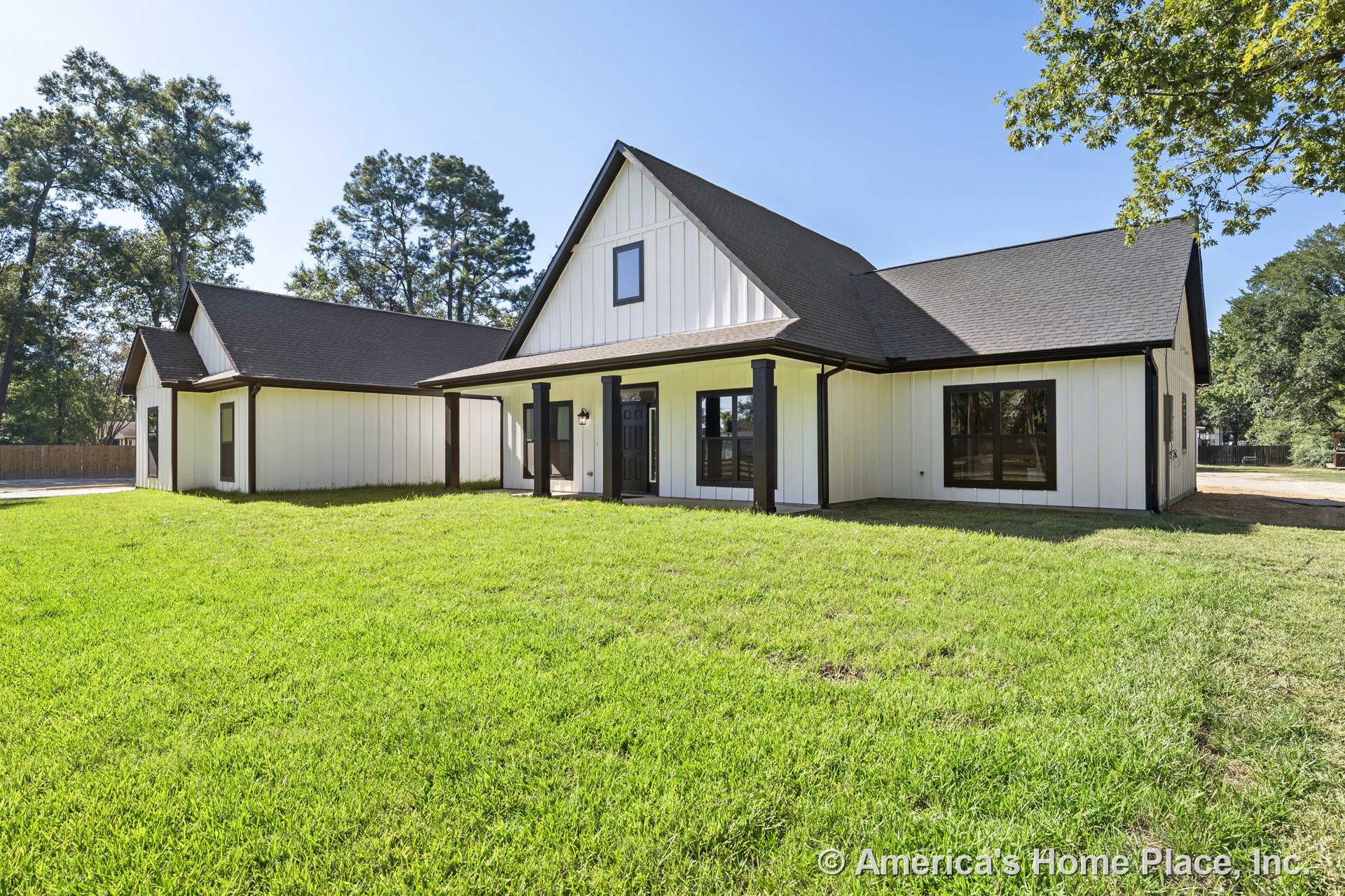 Board and batten siding with contrasting dark trim, covered front porch supported by square columns, gabled roof, multiple windows, and prominent front door.