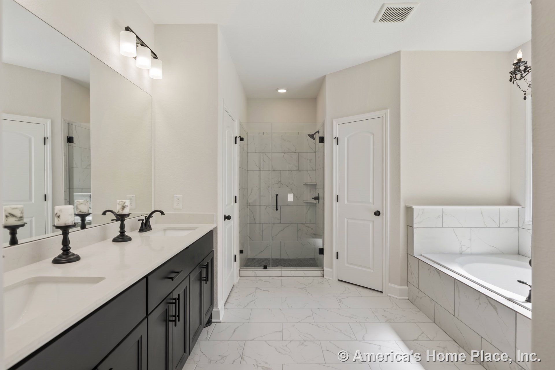 Double vanity with black cabinetry and modern fixtures, glass-enclosed shower, built-in bathtub with marble-look tile surround, large wall mirror, recessed lighting, white walls