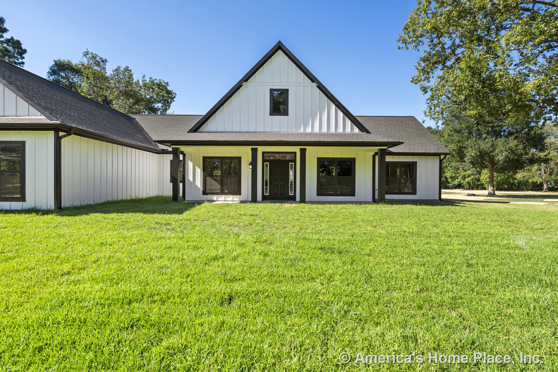 Board and batten siding with dark trim, covered front porch beneath a gabled roof, multiple large windows, and a central front door on modern farmhouse exterior