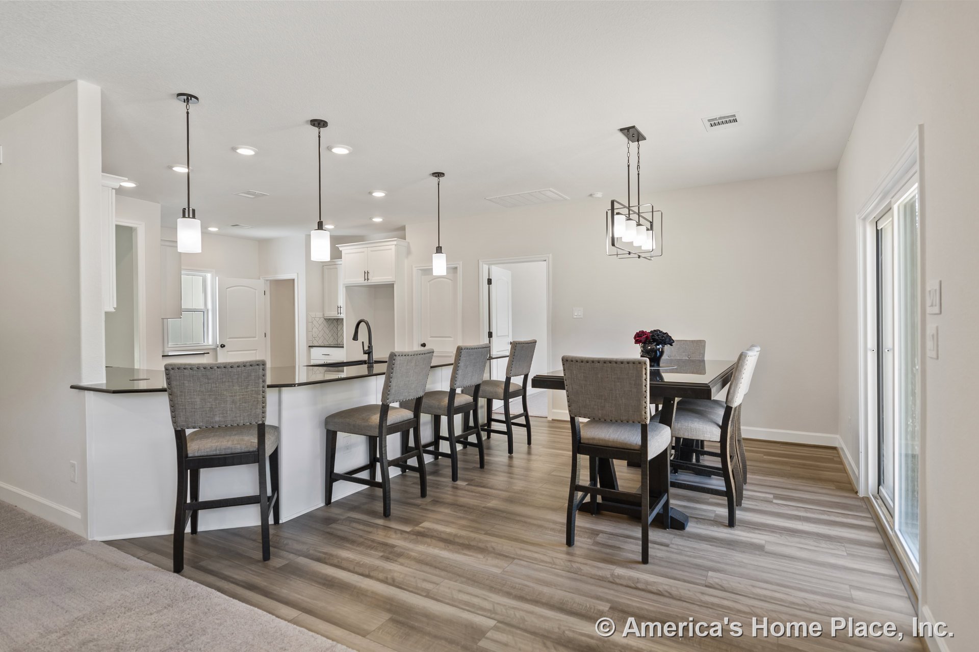Open concept kitchen and dining area with white shaker cabinets, black kitchen island countertop, pendant lights above the island, wood-look plank flooring, recessed lighting in