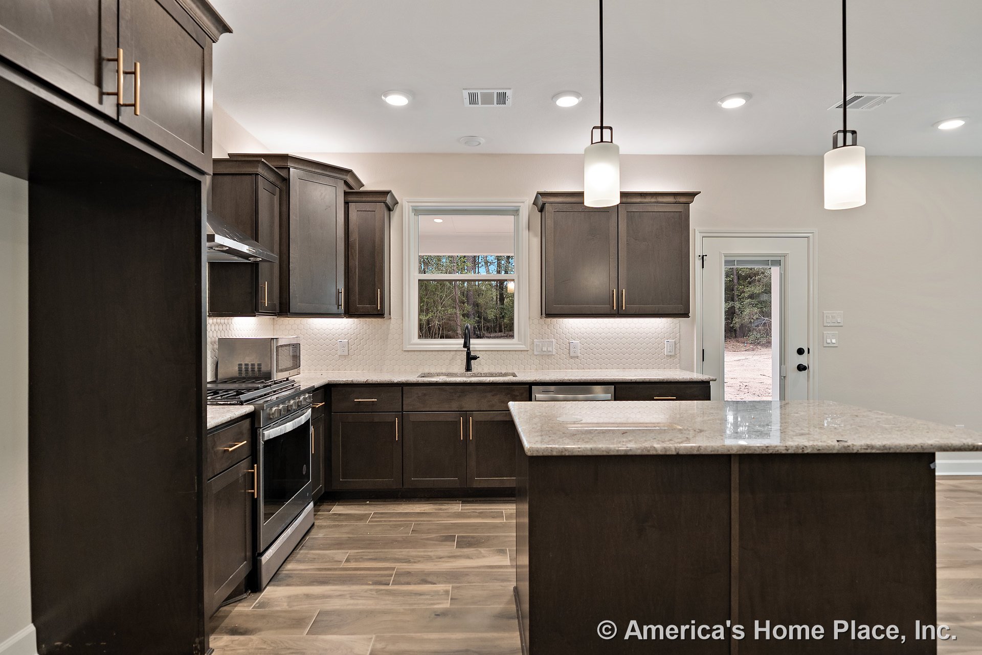 Dark wood kitchen cabinets, granite island countertop, tile backsplash, pendant and recessed lighting, wood-look tile flooring, window above sink, stainless steel appliances.