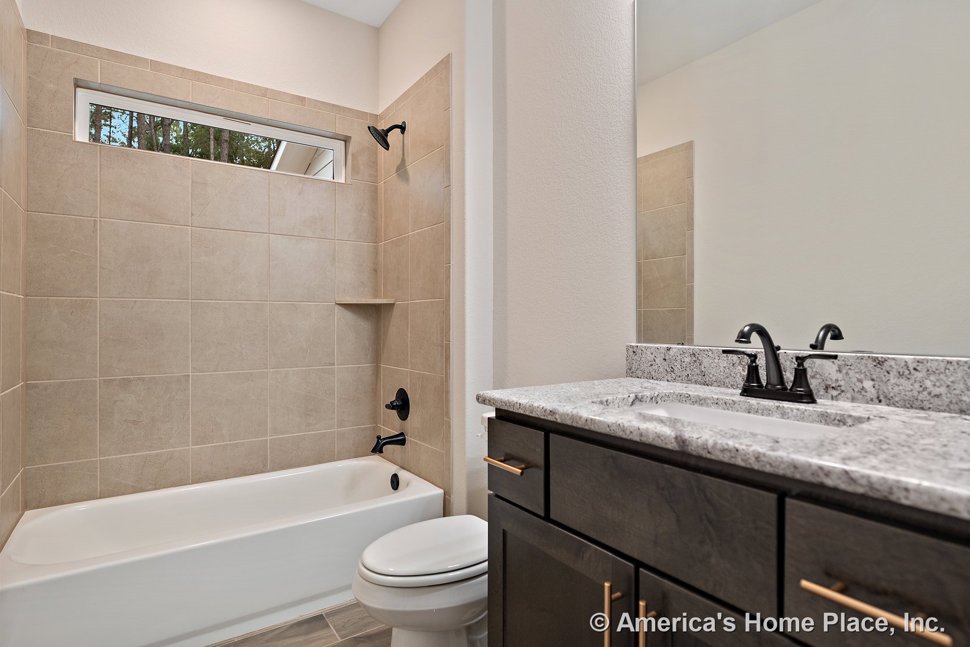 Tiled shower surround with built-in niche, granite countertop vanity with dark wood cabinetry, matte black plumbing fixtures, and horizontal window above the tub.