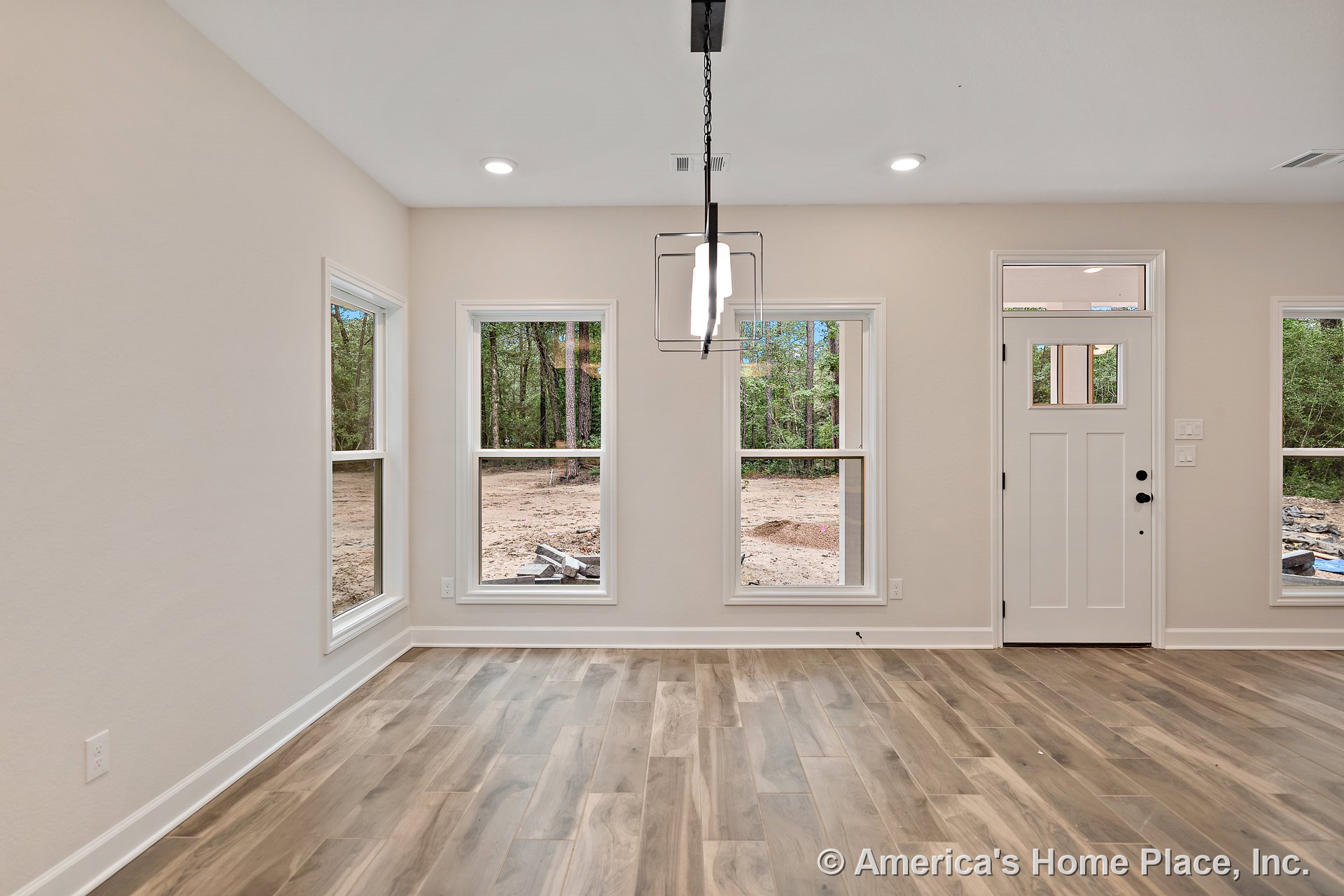 Foyer with wood-look tile flooring, large double-hung windows, modern pendant light, recessed ceiling lights, white trim and baseboards, front door featuring glass insert, and