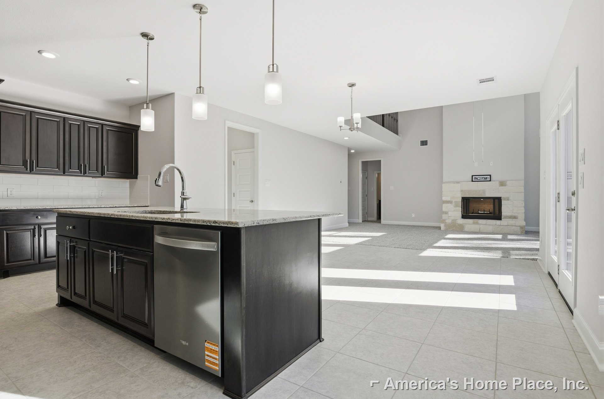 Modern kitchen with grey countertops, stainless steel sink, white cabinetry, built-in fireplace, and metal fixtures