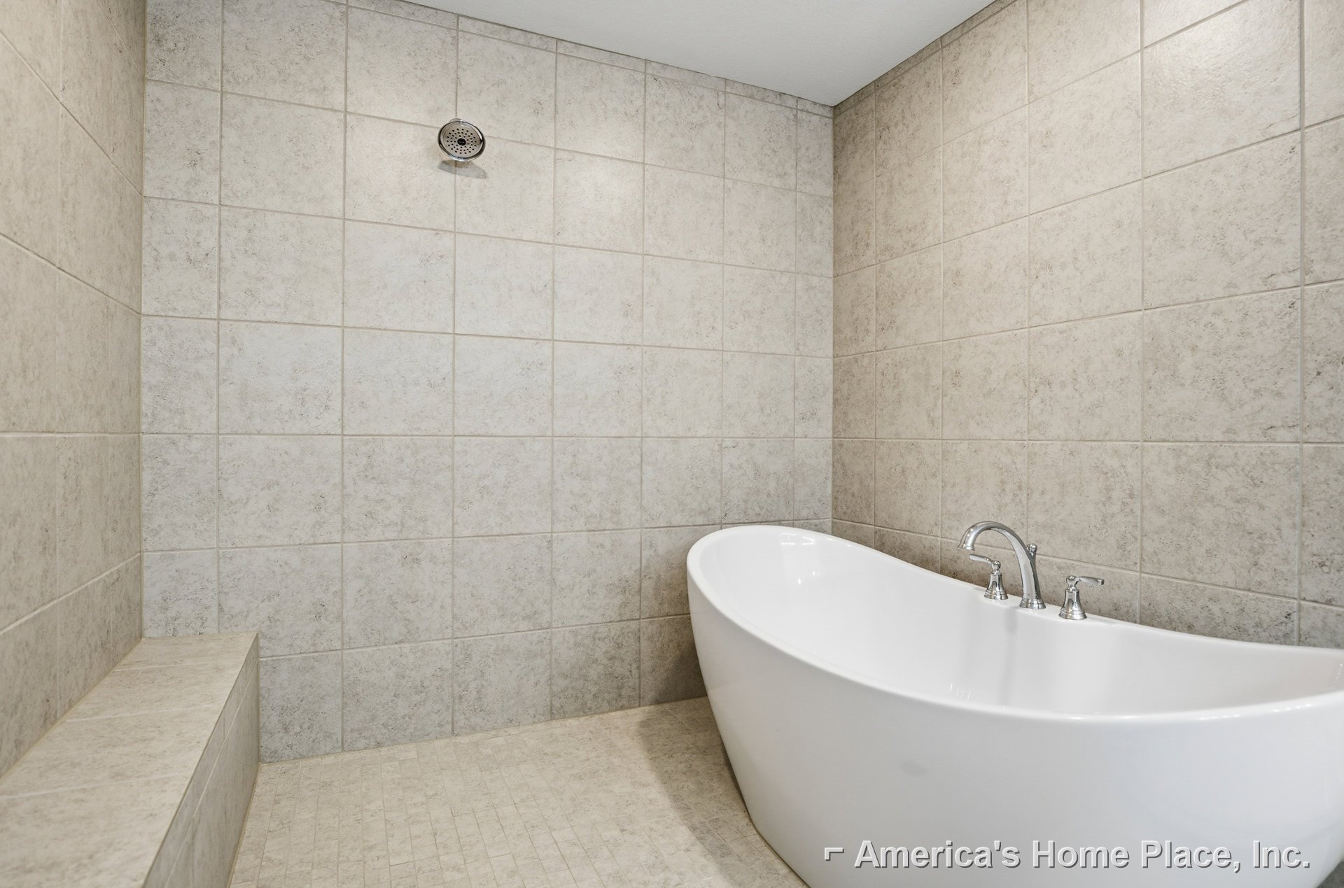 Freestanding white bathtub with chrome faucet and drain, set against light tiled floor and neutral bathroom walls