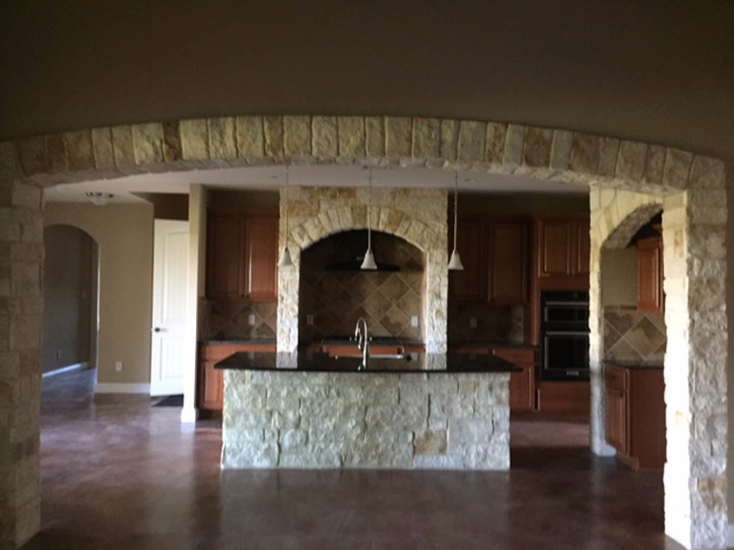 Kitchen featuring a textured stone island, natural wood cabinets, light tile flooring, and recessed ceiling lighting
