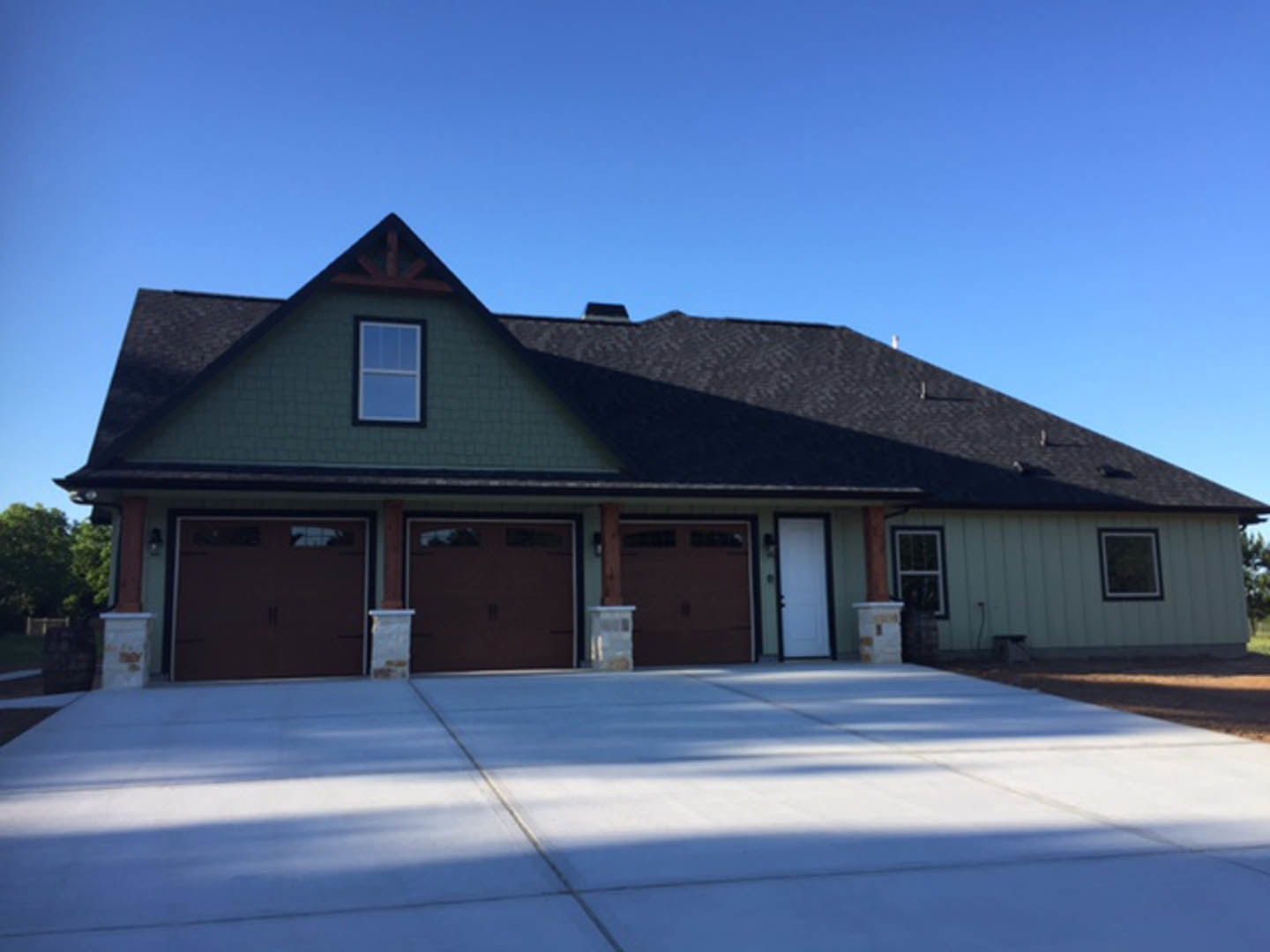 Two-story house with white siding, attached garage, paved driveway, large windows, and blue sky overhead