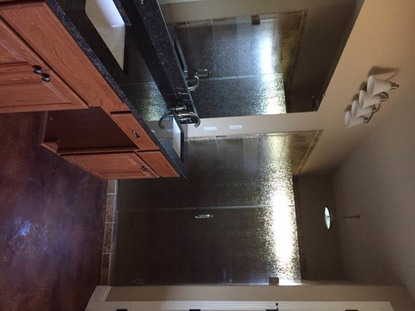 Modern bathroom featuring a white sink with chrome faucet, glass-enclosed shower, light wood cabinetry, and neutral plaster walls.