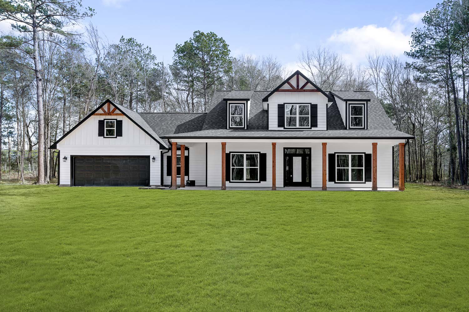 Two-story farmhouse with black and white roof, white framed windows, black front door with rectangular window, and green lawn bordered by trees