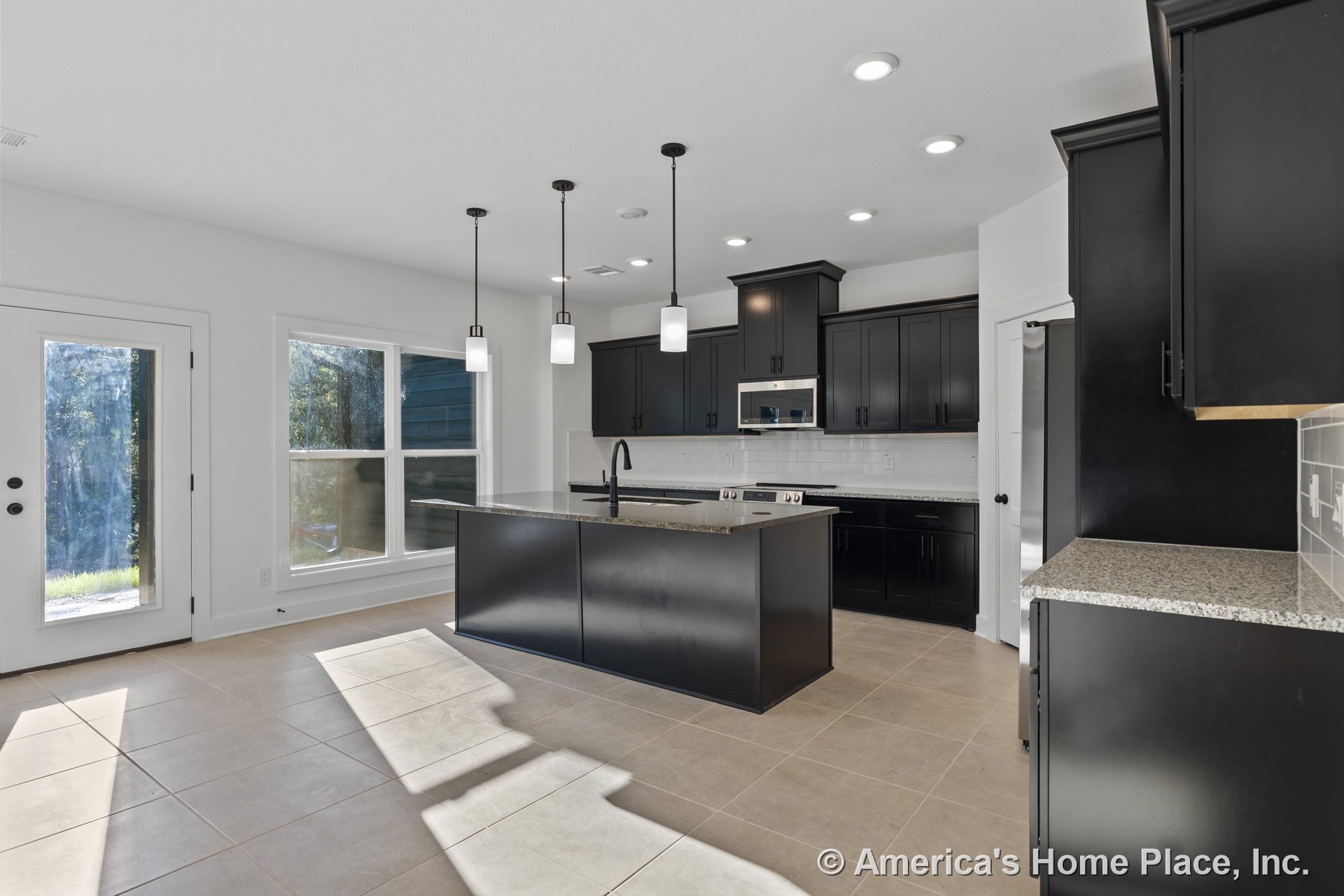 Black shaker cabinets with granite countertops, pendant lights above a central island, large tile flooring, white subway tile backsplash, double window and glass door, built-in