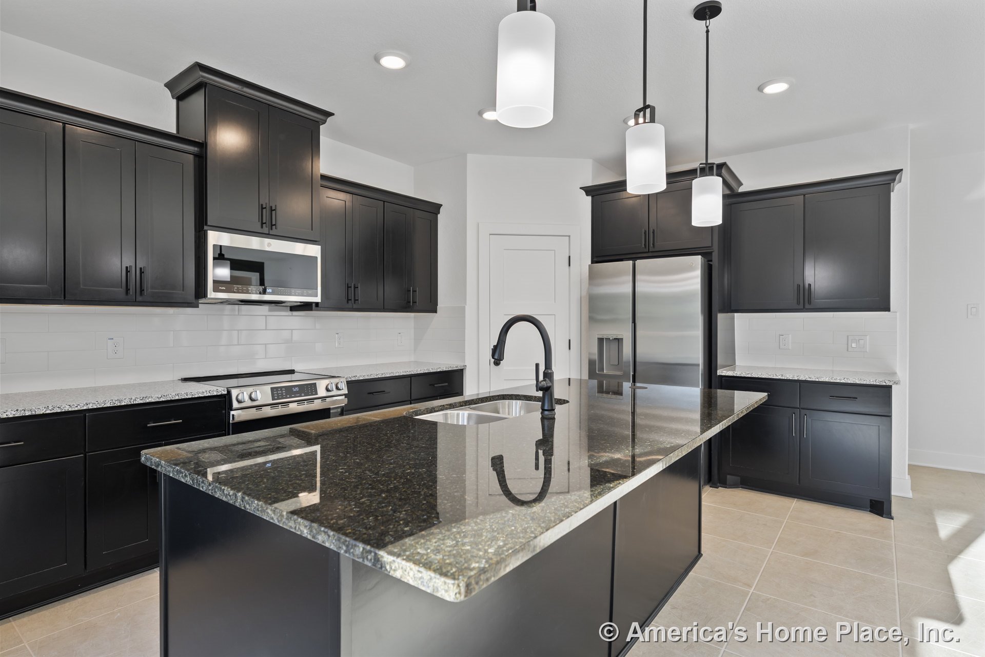 Spacious kitchen with large island, black shaker cabinets, granite countertops, stainless steel refrigerator, built-in microwave, white subway tile backsplash, pendant and recessed