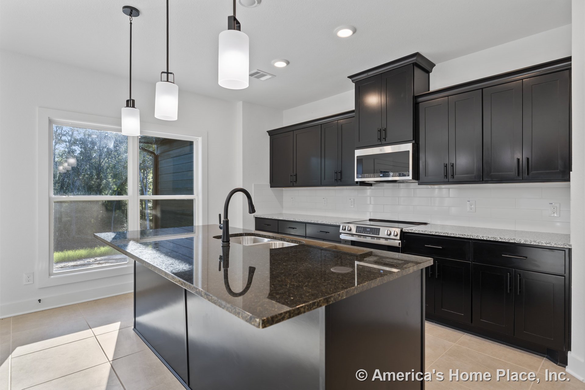 Spacious kitchen with dark shaker cabinets, granite countertops, large island featuring an undermount sink, white subway tile backsplash, built-in microwave, pendant and recessed