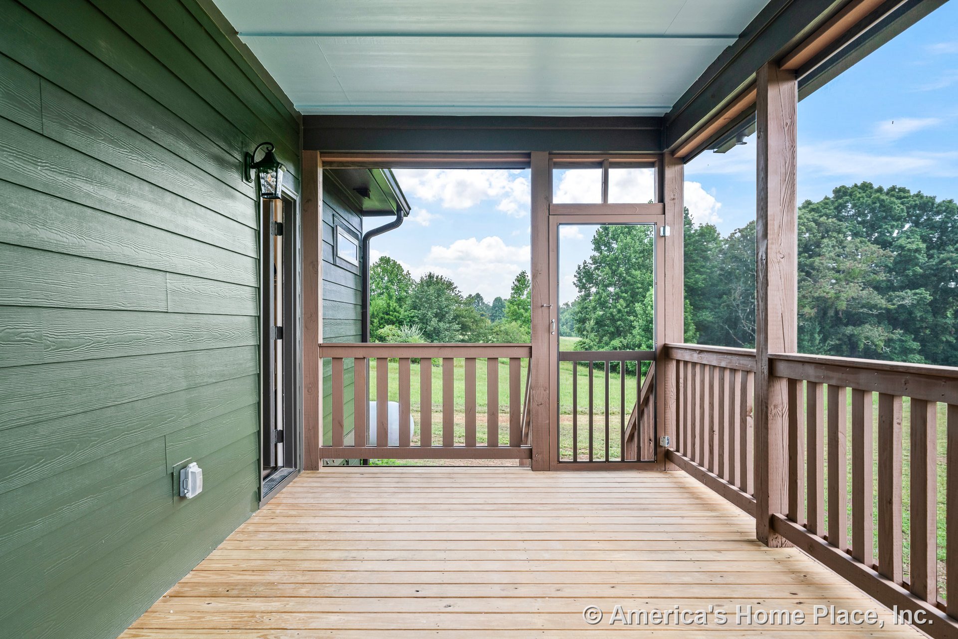 Covered porch with wood plank flooring, green horizontal siding, screened enclosure, wood railings and posts, exterior wall light fixture, painted ceiling, and trim detailing.