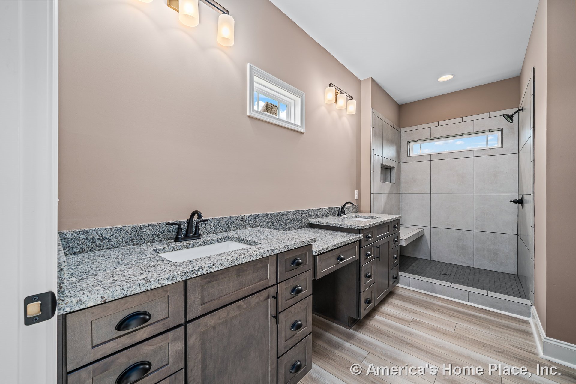 Double vanity with granite countertops and dark wood cabinetry, matte black fixtures, large walk-in tiled shower with built-in bench and horizontal window, neutral tile flooring