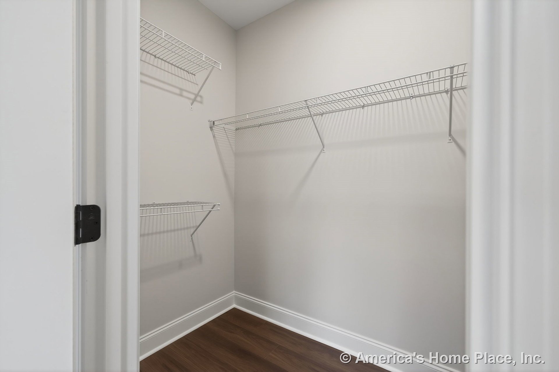 Walk-in closet with wire shelving, wood-look flooring, white baseboard trim, neutral painted walls, and open door entry.