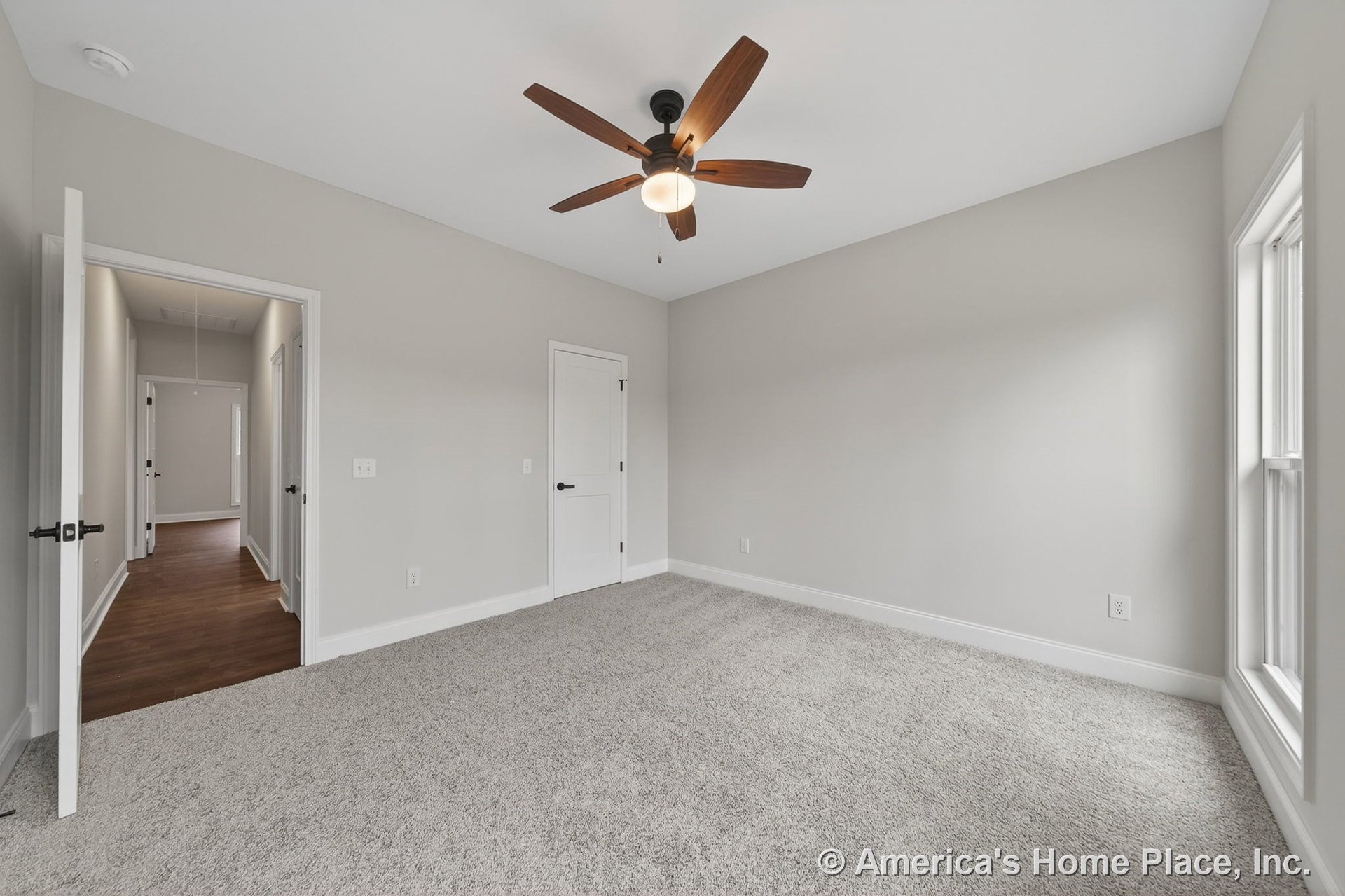 Bedroom with light gray carpet flooring, white baseboards and trim, ceiling fan with integrated light fixture, double-pane windows allowing natural light, neutral gray walls, and