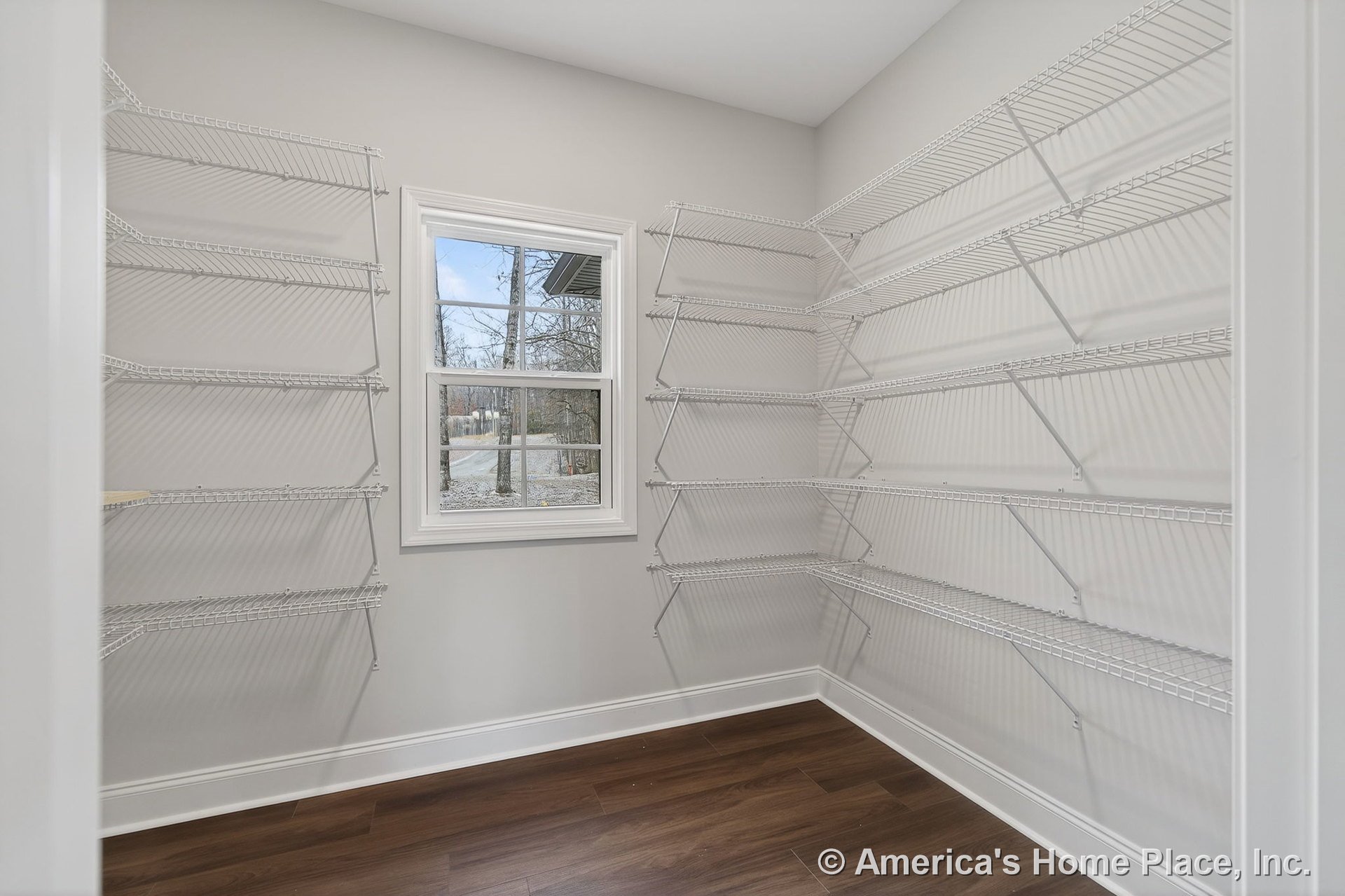 Walk-in pantry with multiple white wire shelves, double-hung window, wood-look flooring, white trim, and neutral wall color.