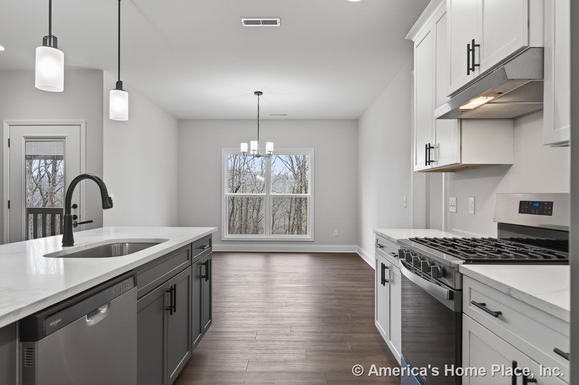 White upper cabinets and dark lower cabinets with quartz countertops, stainless steel gas range, and pendant lighting over the kitchen island; open dining area features large