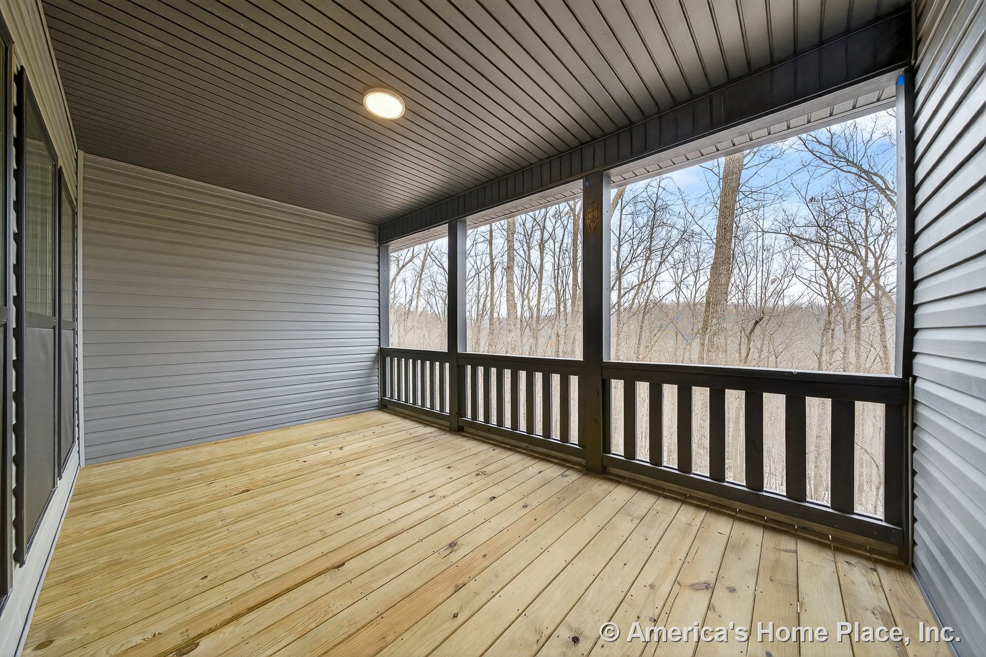 Screened-in porch with wood plank flooring, vinyl siding walls, dark railing trim, tongue-and-groove ceiling, built-in ceiling light, and screened windows.