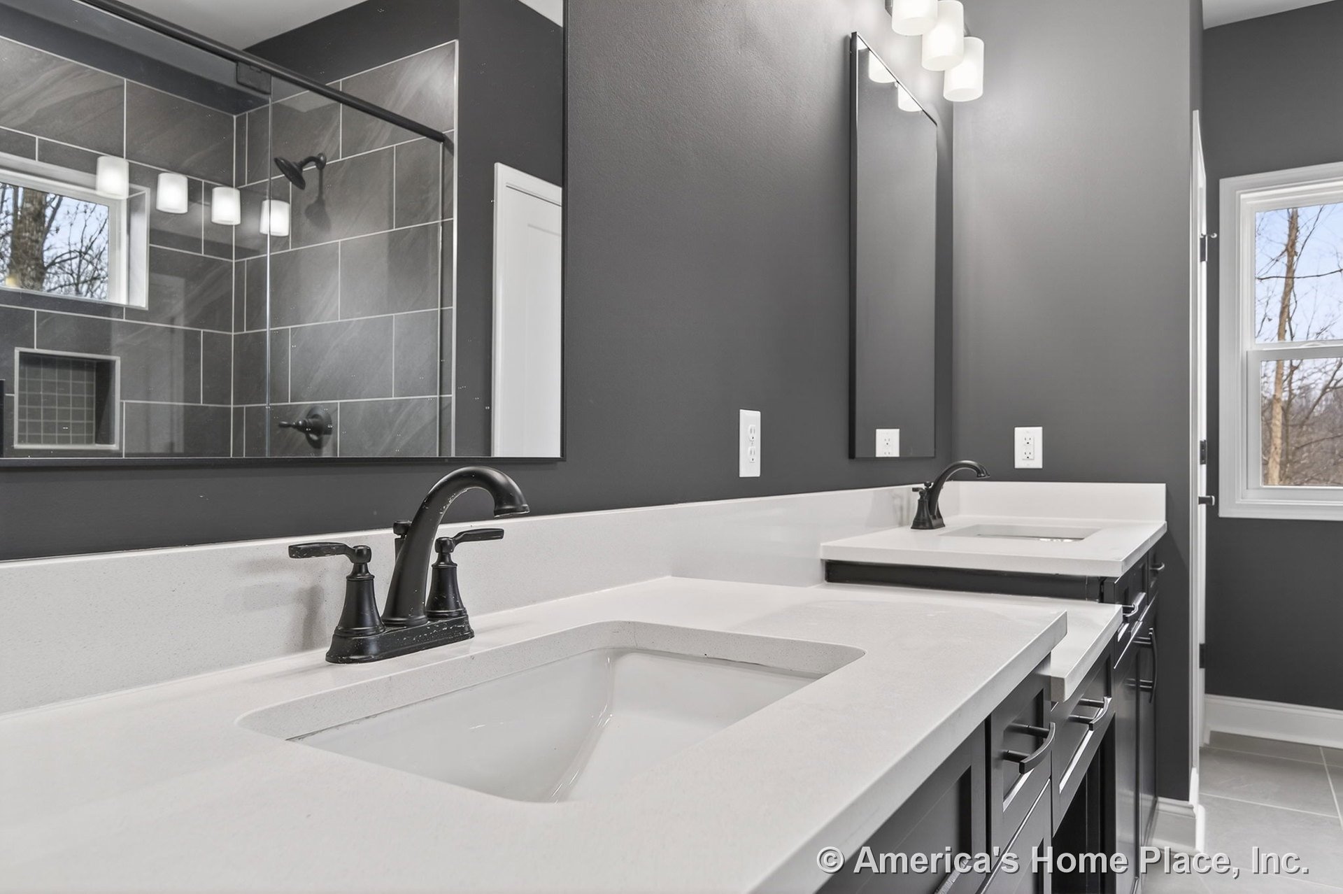 Dual sink vanity with white quartz countertops, black cabinetry and hardware, large wall mirrors, matte black faucets, tile flooring, built-in lighting, window, and gray painted