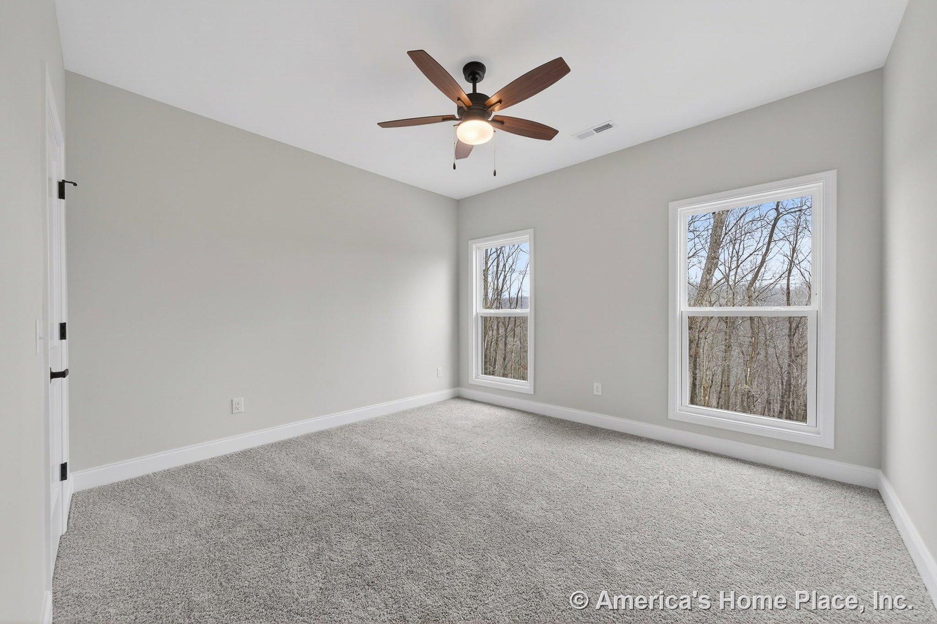 Bedroom with light gray carpet flooring, white trim and baseboards, two large windows allowing natural light, neutral wall color, ceiling fan with built-in lighting, and interior